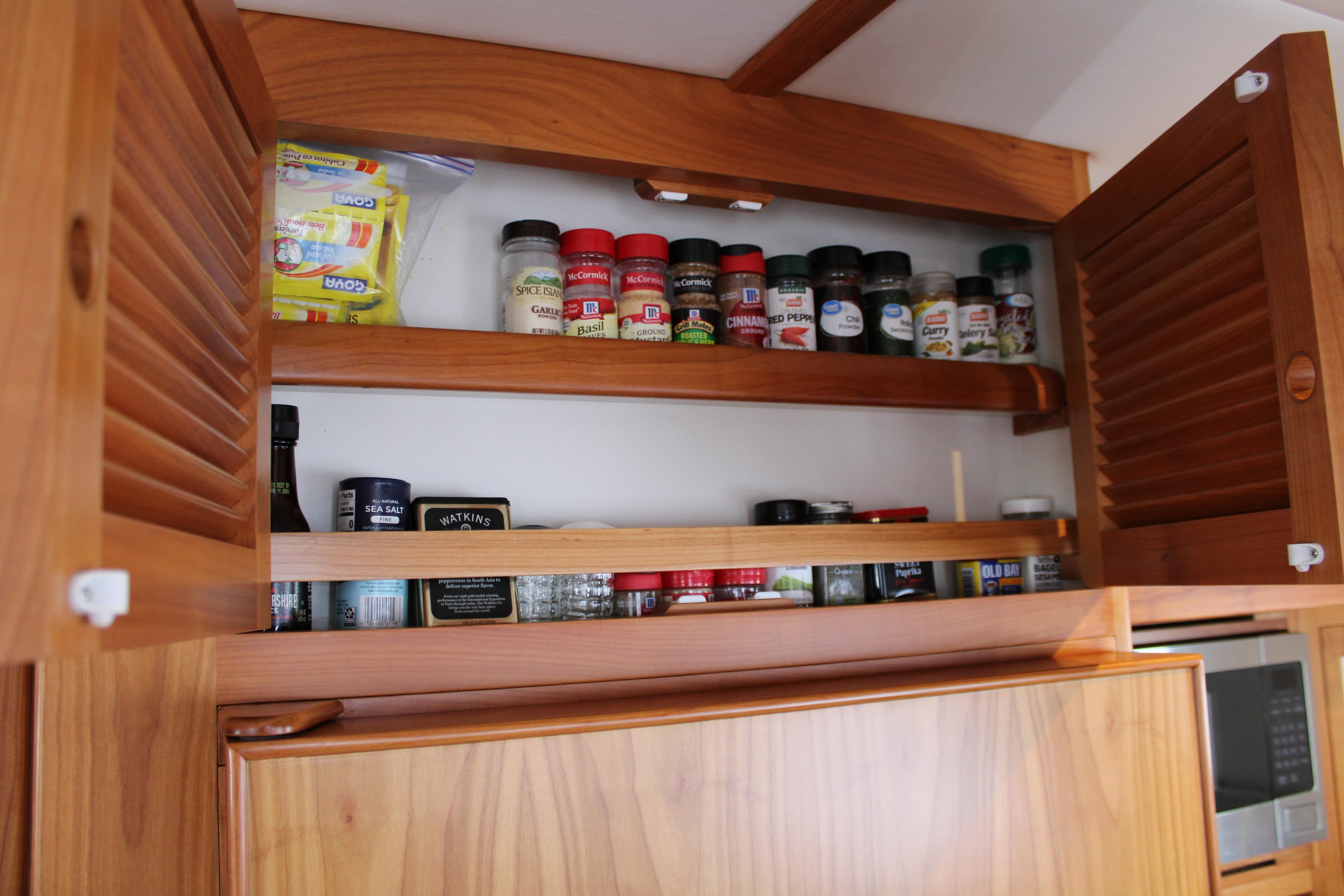 Wooden kitchen cabinet with spices and pantry items on a 2023 Krogen Express 52' yacht.