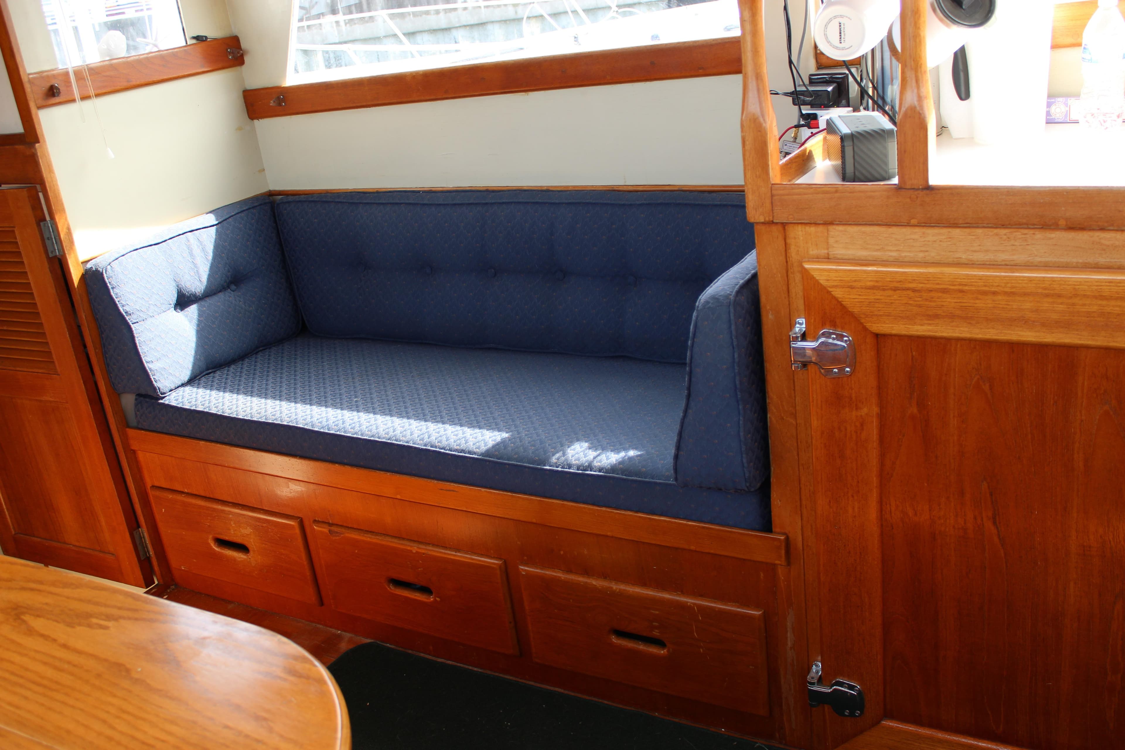 Interior of 1971 Grand Banks 36 Classic with blue cushioned seating and wooden cabinetry.