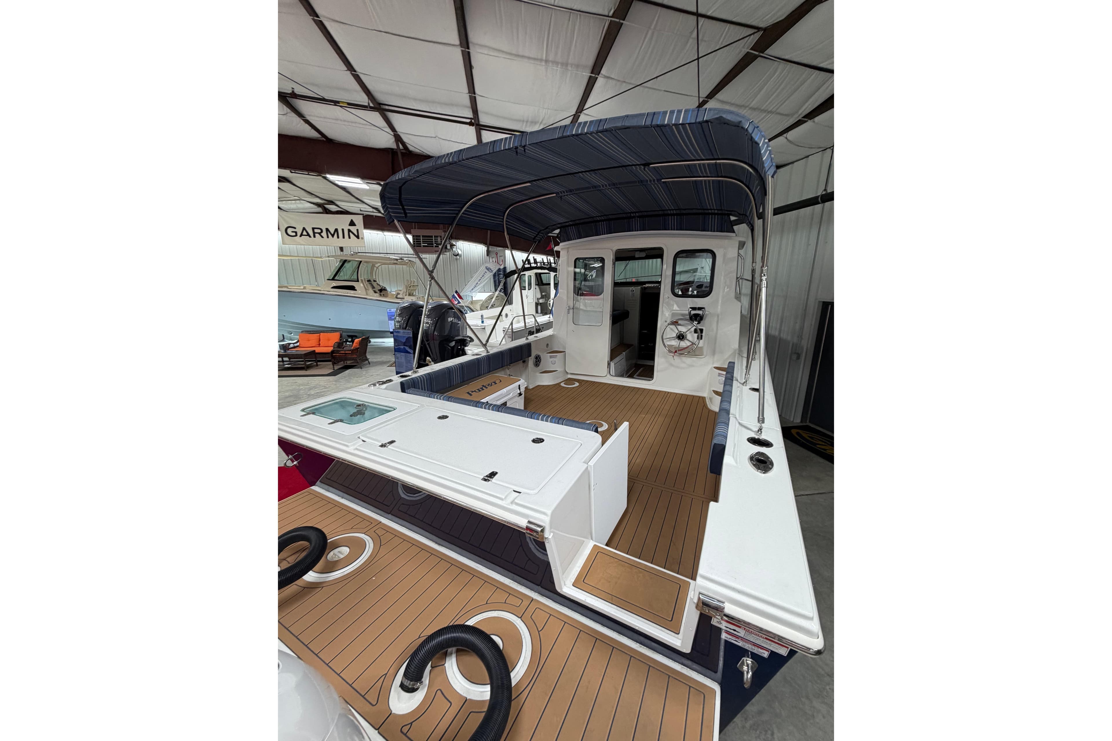 2026 Parker 257 Explorer boat with canopy, displayed indoors, featuring teak flooring.