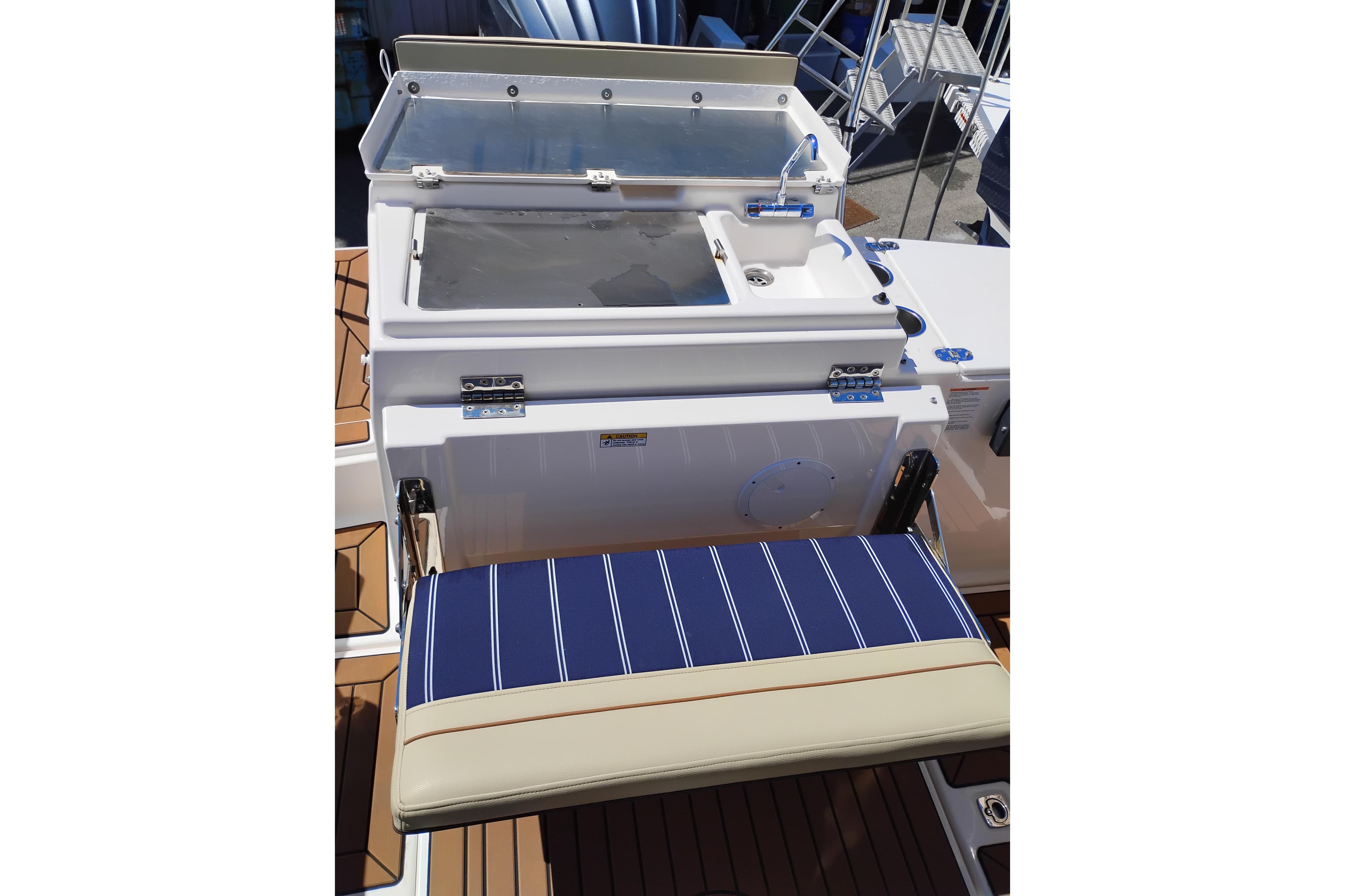 2024 Ranger Tugs R-27 boat with a striped cushioned seat and utility sink.
