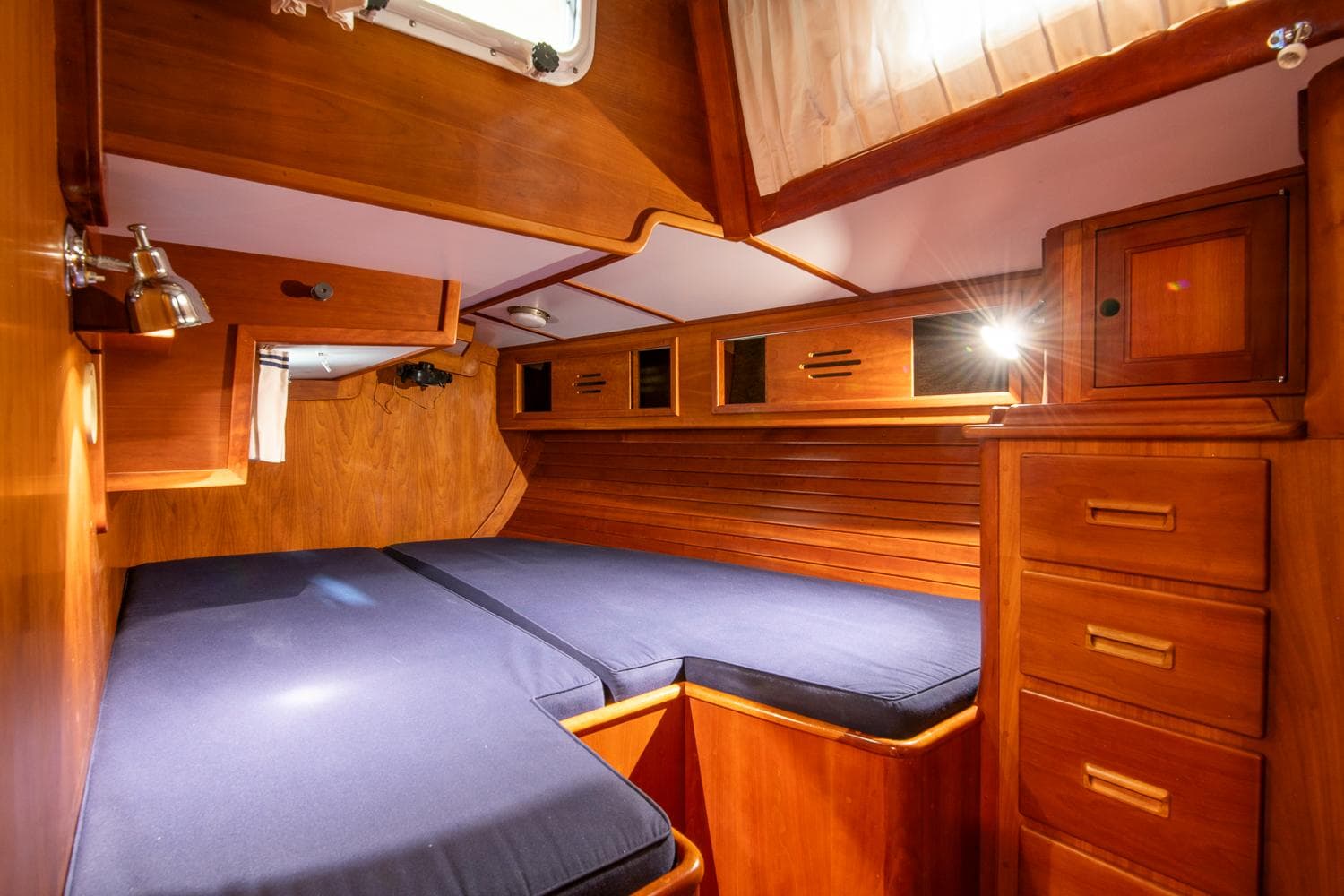 Cabin interior of 1993 Hinckley Sou'wester 51 sailboat with wooden finish and blue bedding.