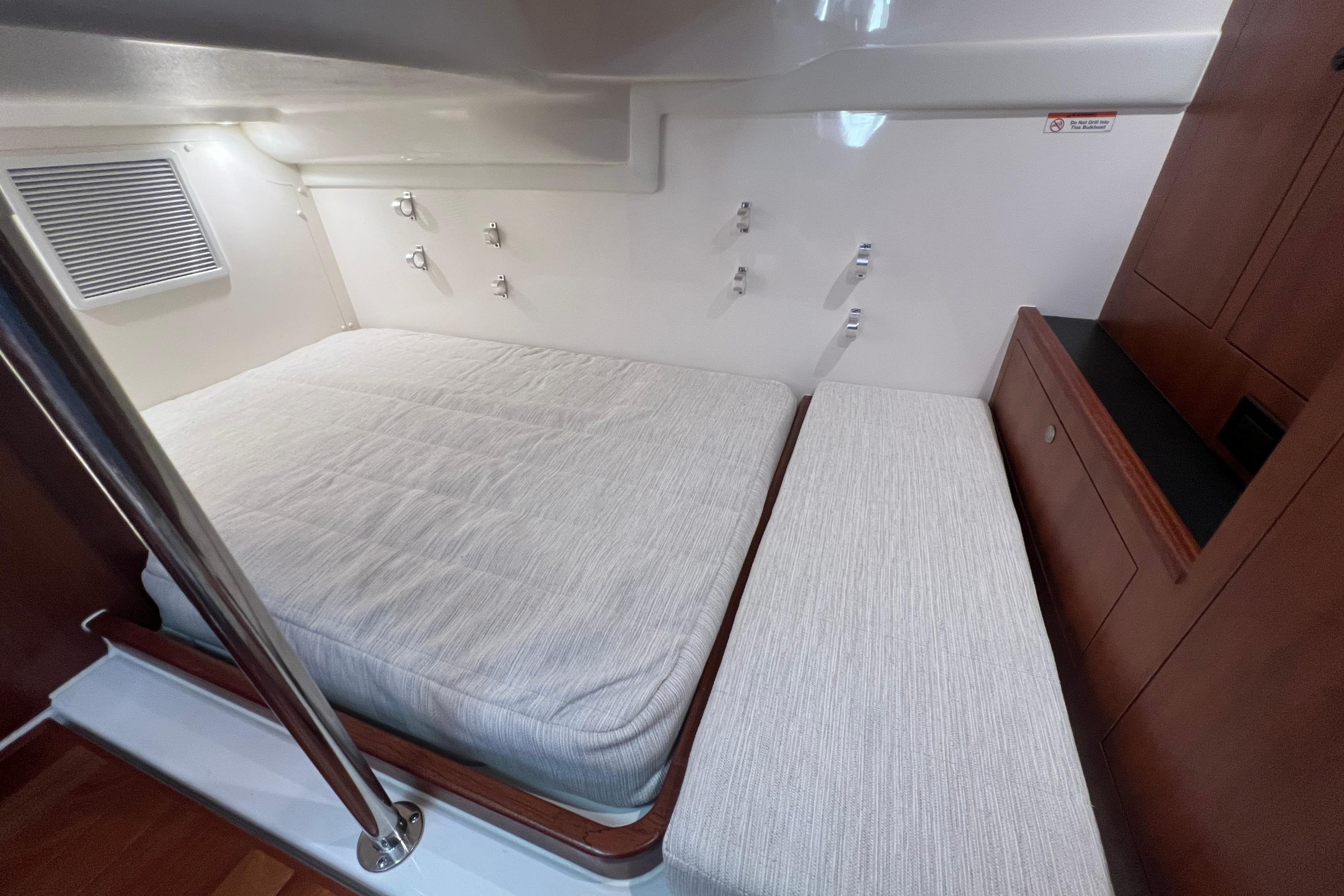 2026 Pursuit OS 355 Offshore cabin interior with bed and wooden cabinetry.