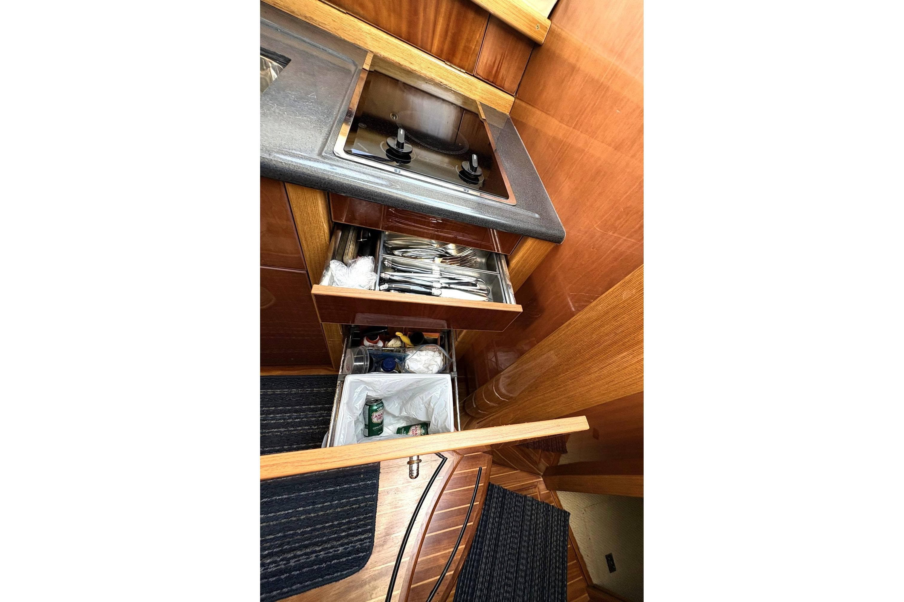 2003 Sealine F42/5 yacht kitchen with stove, open drawers, and wooden cabinetry.