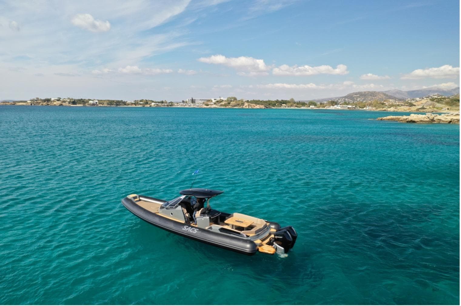 2023 SACS Strider 11 boat on clear turquoise water, scenic coastal background.