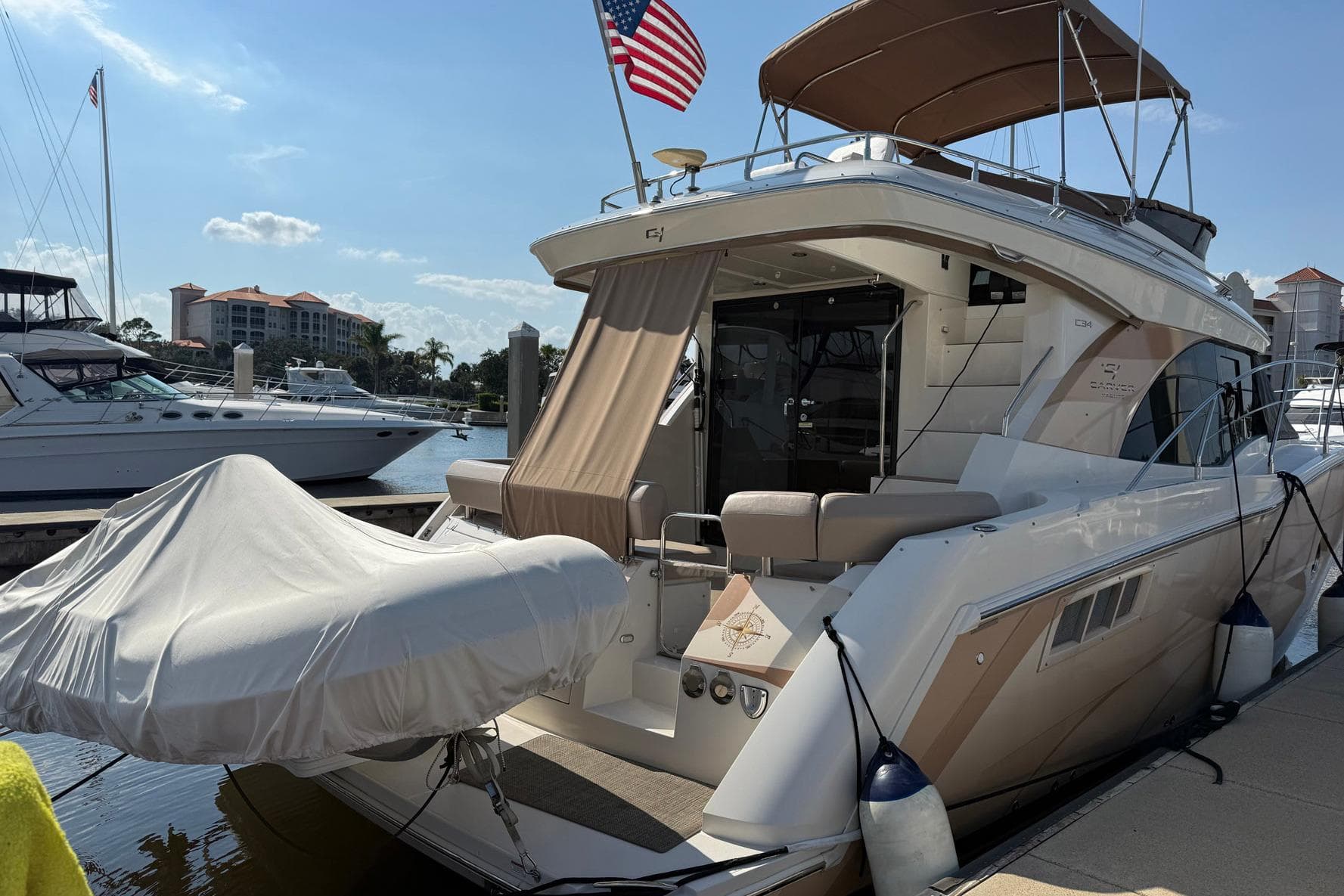 2013 Carver C34 yacht docked, featuring covered tender and American flag.