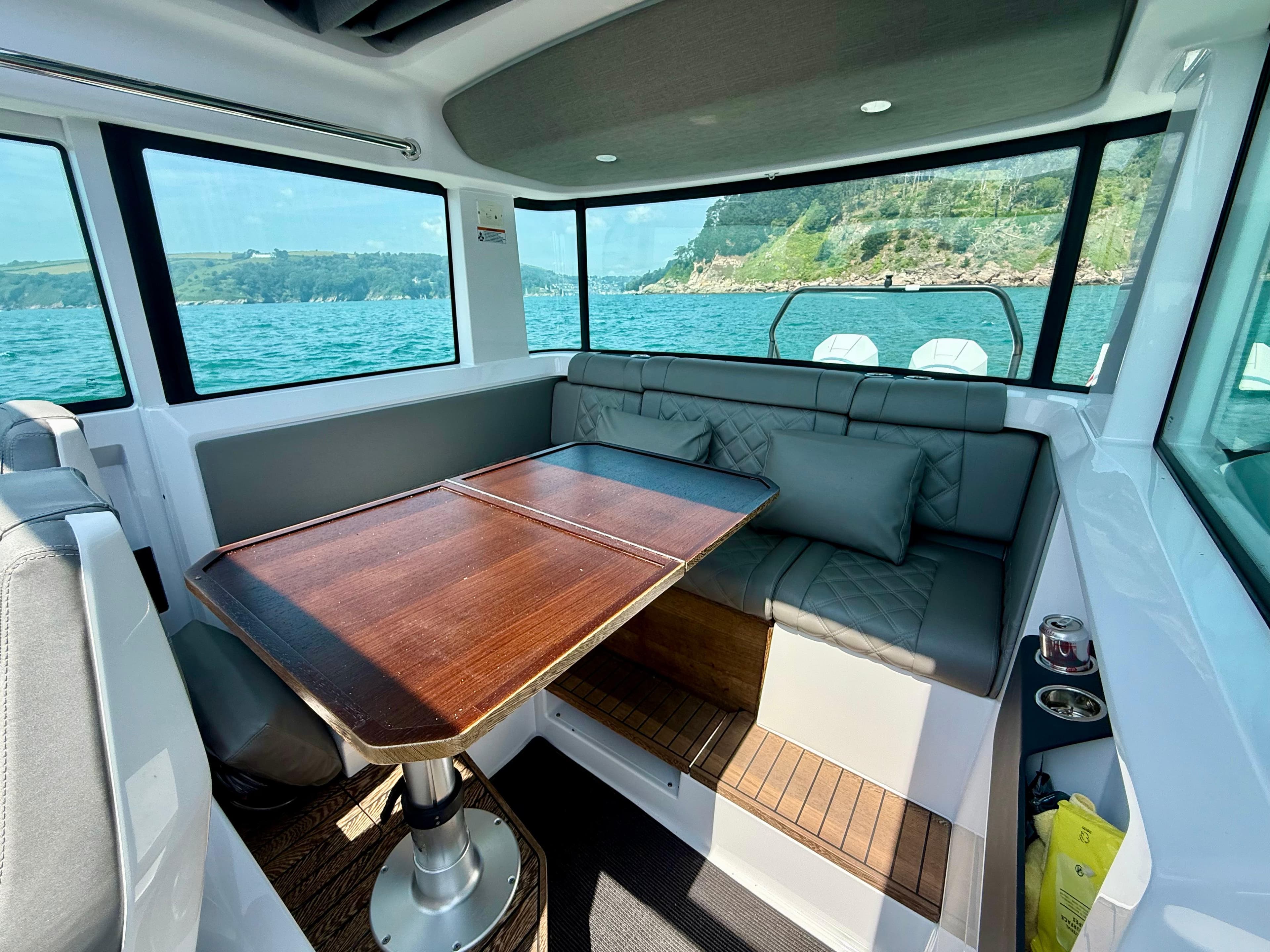 Interior of 2020 Axopar 37 Cross Cabin with seating and wooden table, ocean view.