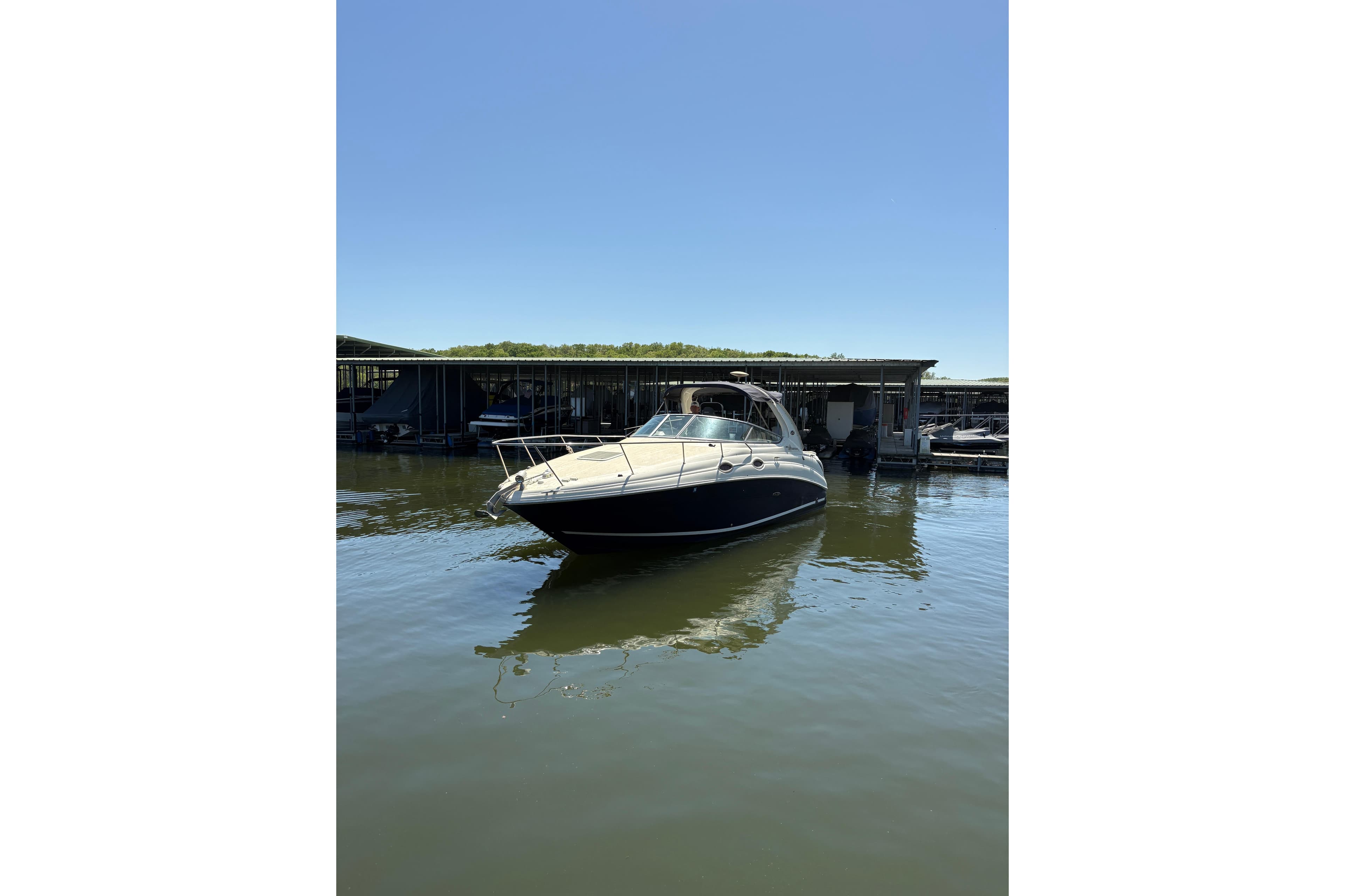 2005 Sea Ray Sundancer 280 boat docked on calm water under clear blue sky.