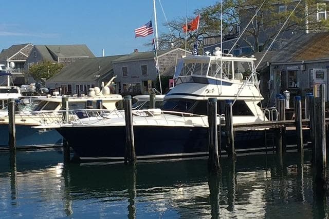 1988 Viking 45 Convertible yacht docked at a marina with flags and waterfront buildings.