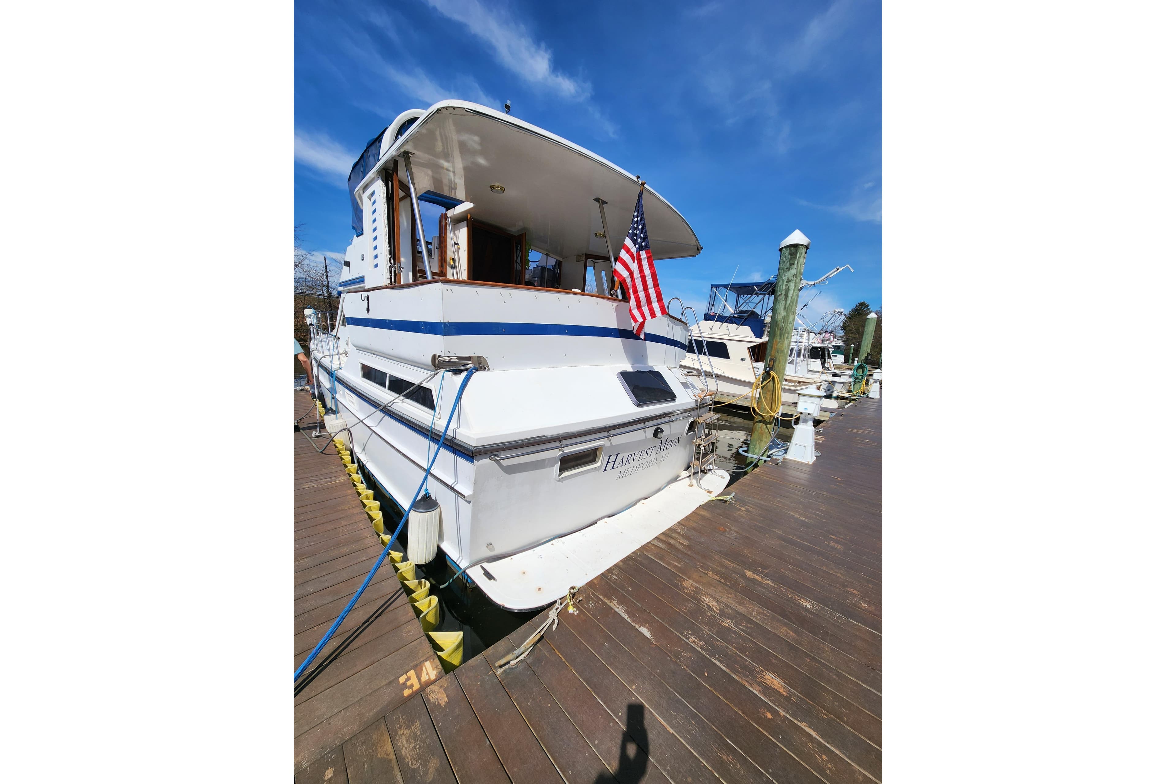 1987 Jefferson 42 SE Sundeck Motor Yacht docked with American flag, clear sky background.