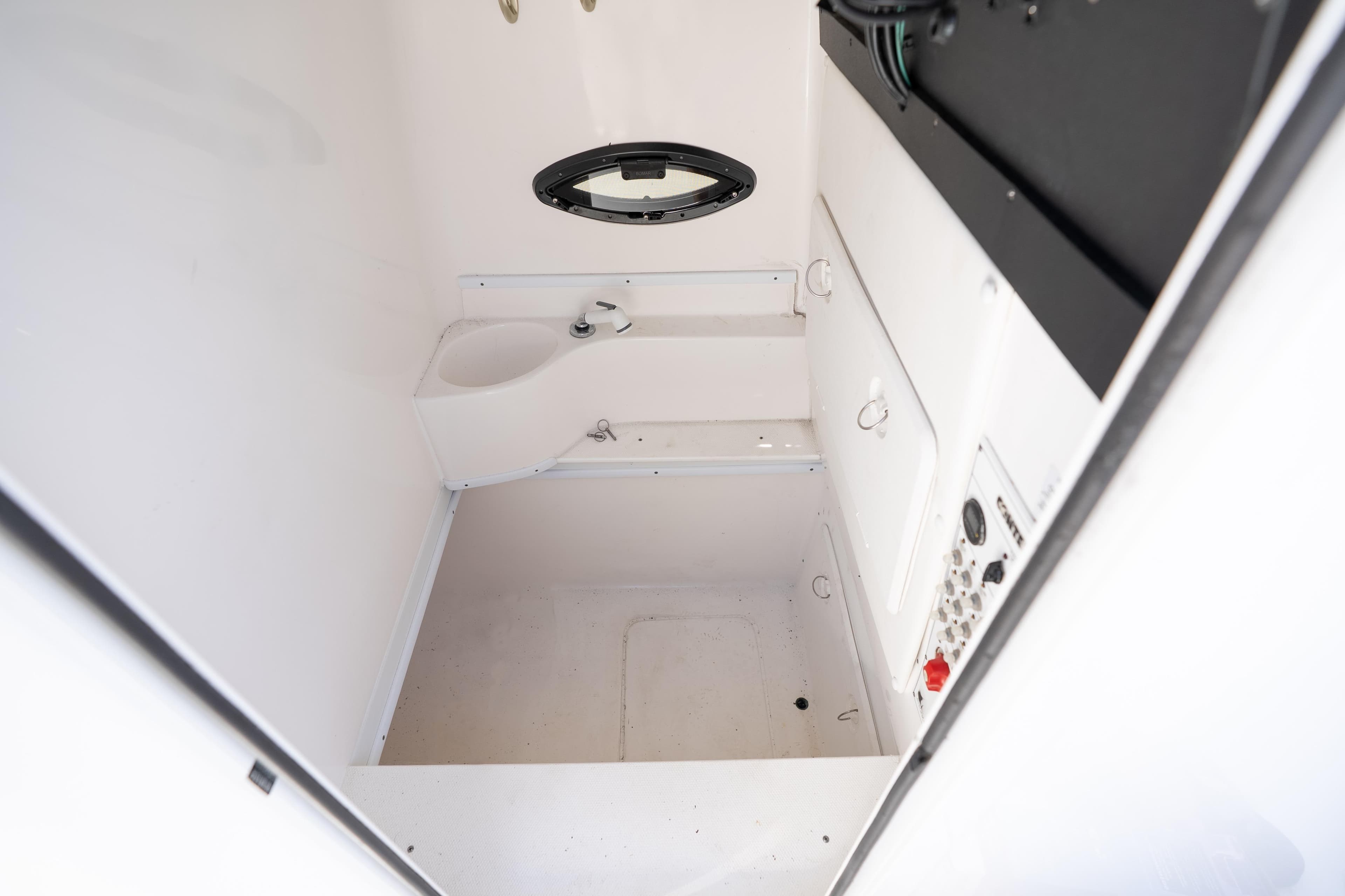 Interior of 2022 Contender 35 ST boat, featuring a compact, white marine bathroom.