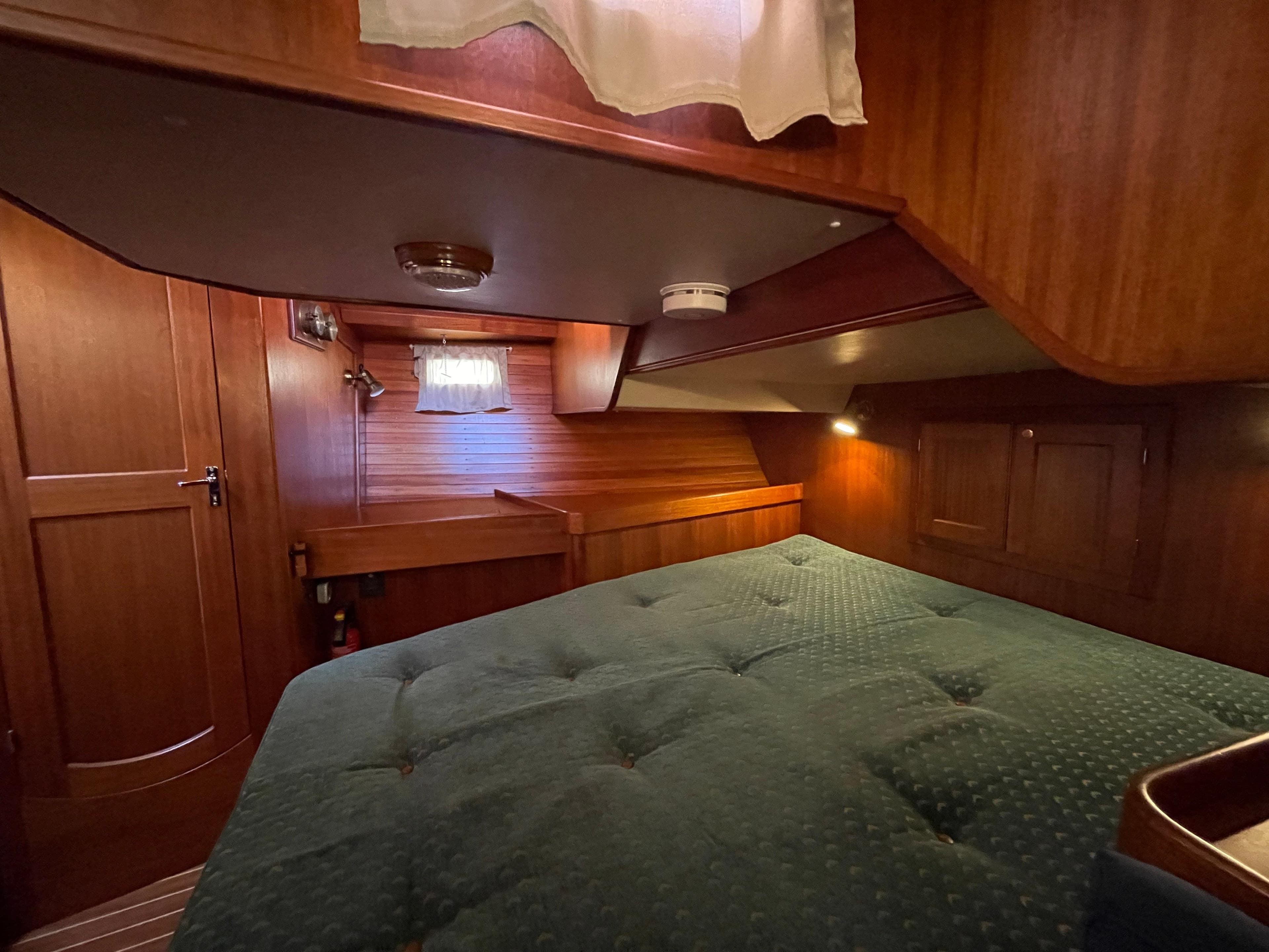Cozy cabin interior of 2000 Regina 43 yacht with wooden finish and green bedding.