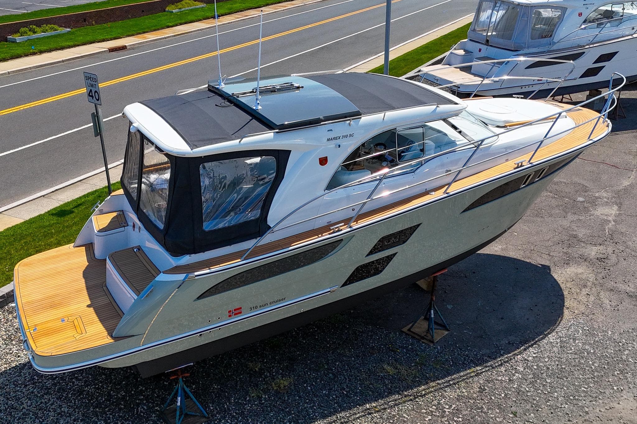 2026 Marex 310 Sun Cruiser boat displayed on a stand near a road.