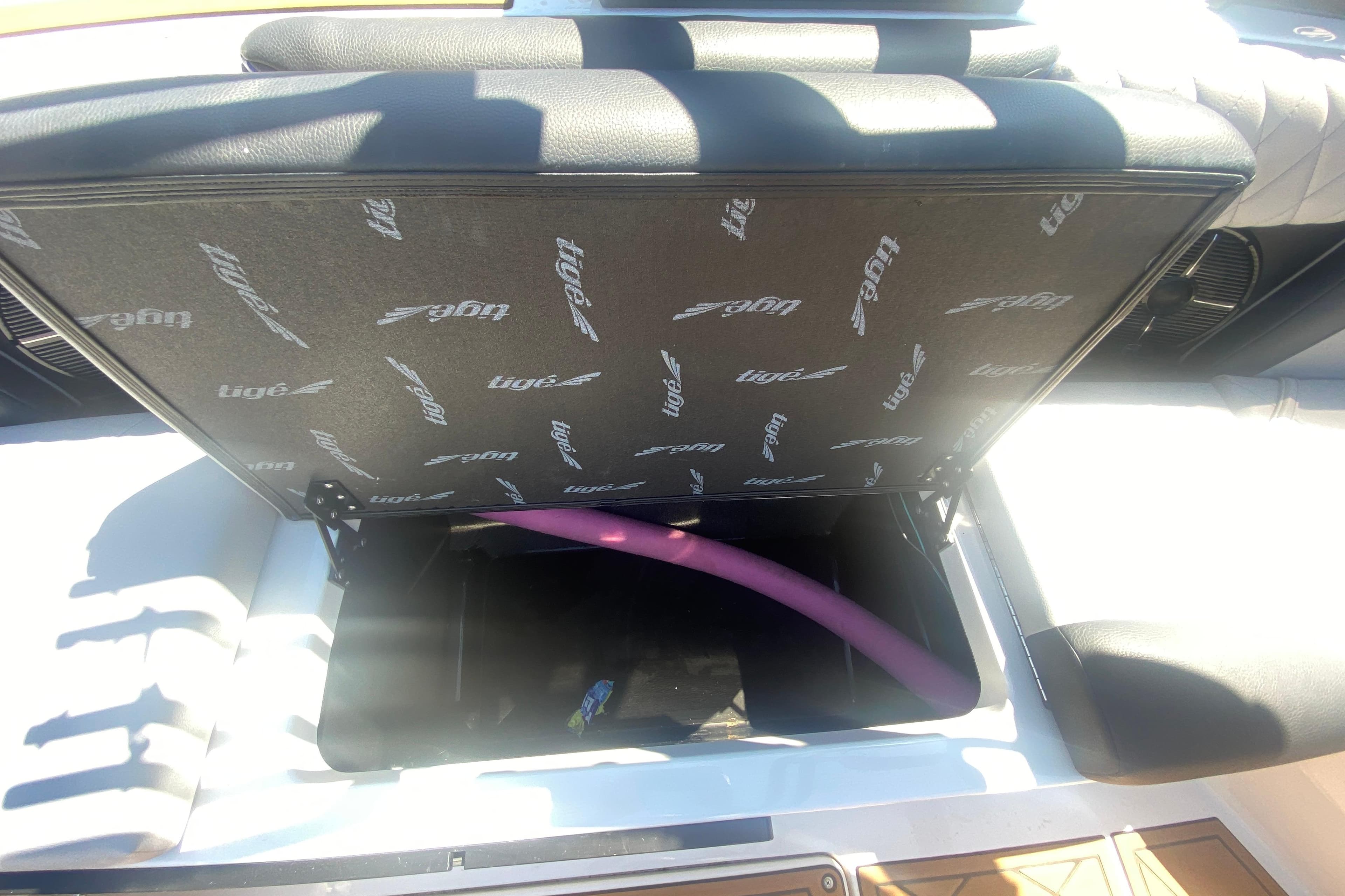 Open storage compartment in 2021 Tigé Z3 boat with visible pink pool noodle.