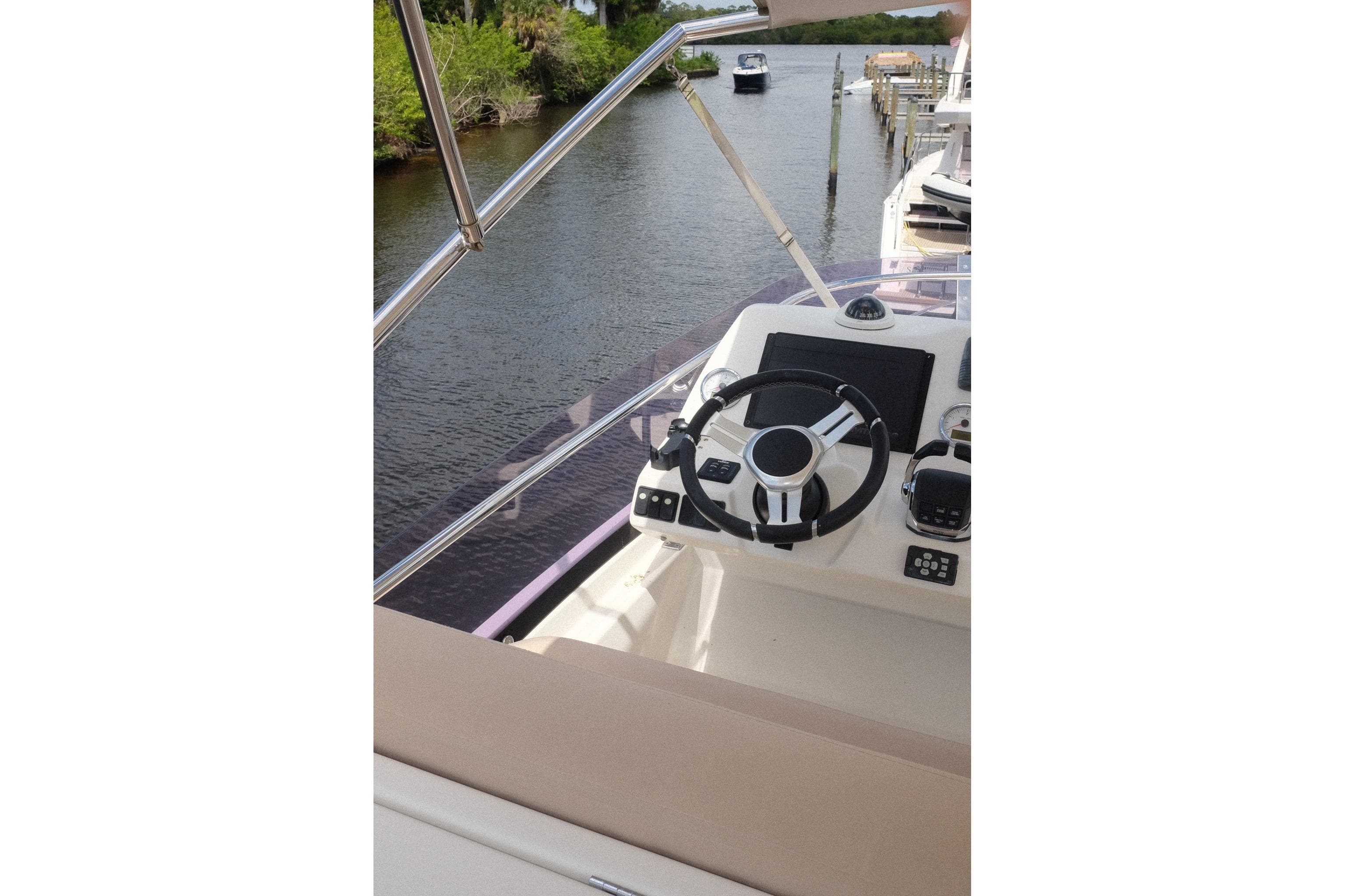 Helm of a 2016 Prestige 500 yacht, featuring modern controls and a scenic waterway view.