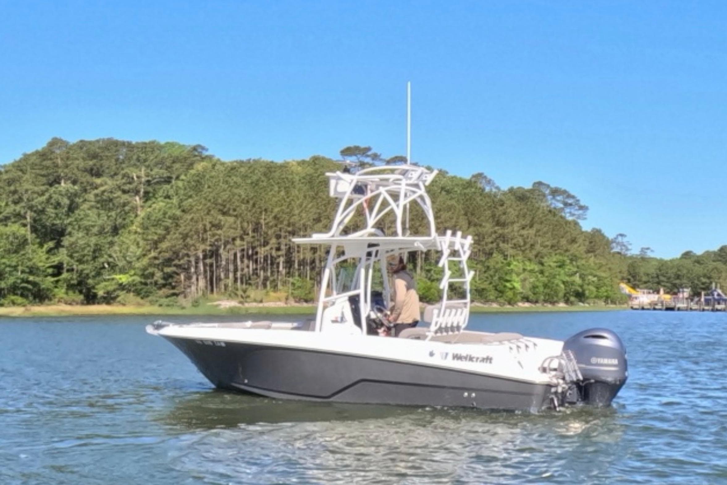 2020 Wellcraft 222 Fisherman boat cruising on a scenic lake with forested shoreline.
