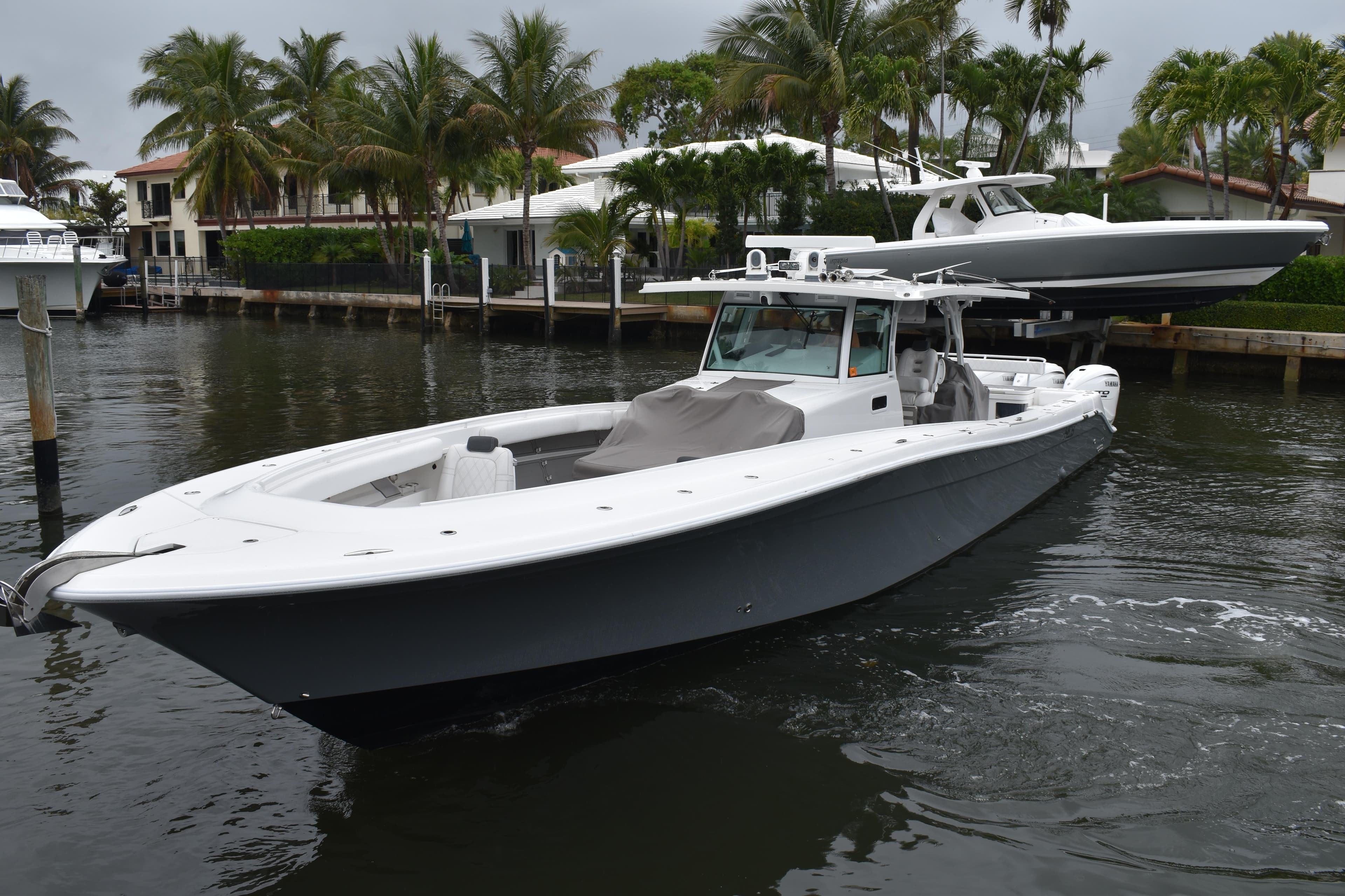 2019 HCB 53 Suenos boat docked near palm trees and waterfront homes.