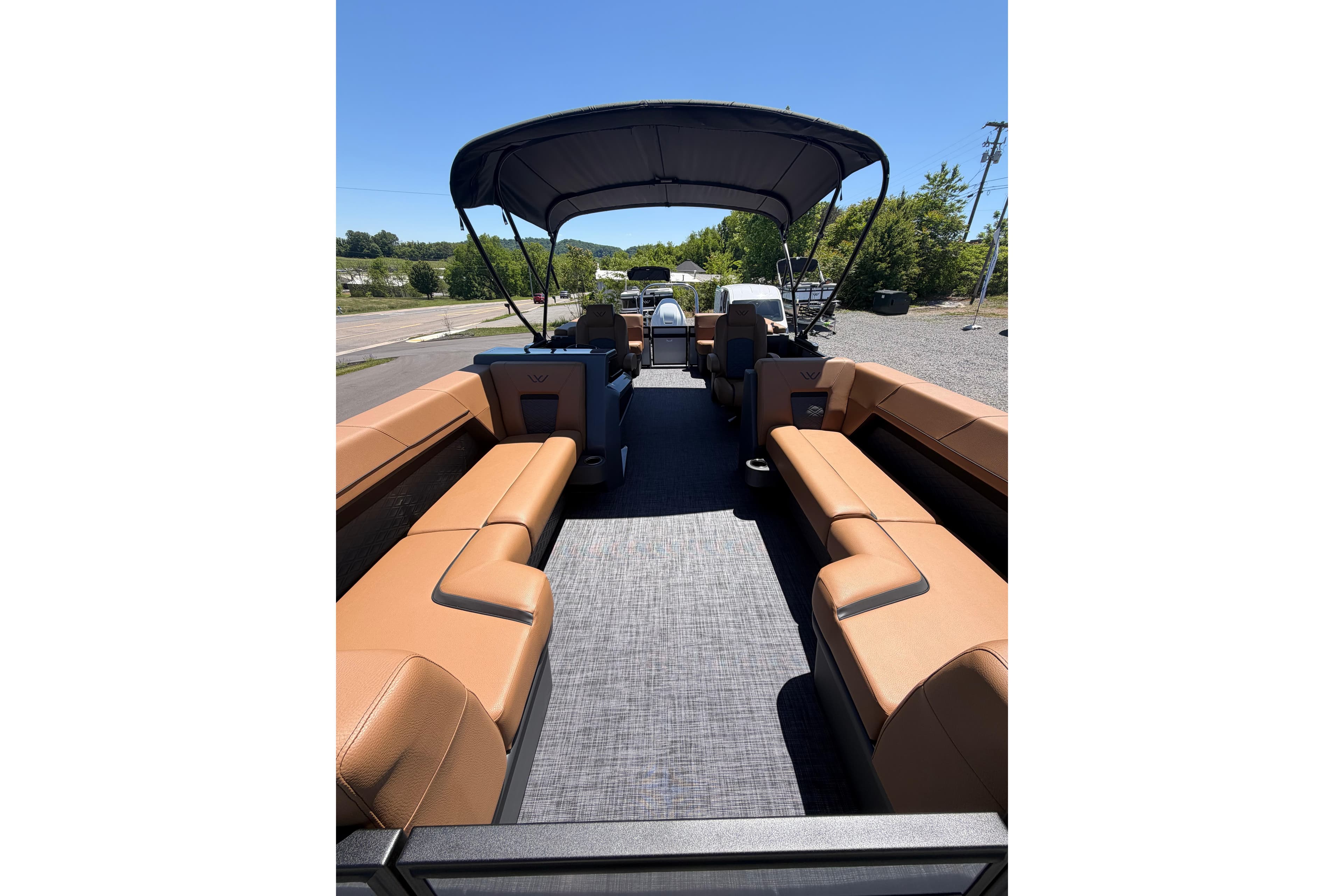 Interior view of 2026 Whisper V23 RLS pontoon boat with tan seating and canopy.