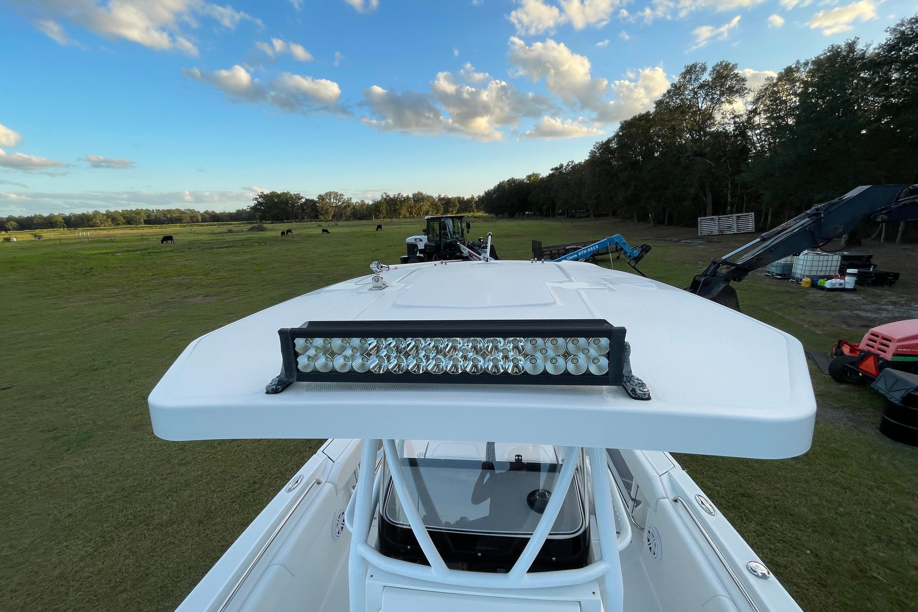 2022 Blackfin 252 CC boat with LED light bar, parked on grassy field under blue sky.