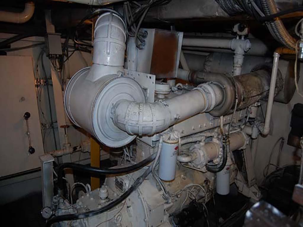 Engine room of a 1985 Custom Serodino Dinner Boat, showcasing complex machinery and piping.