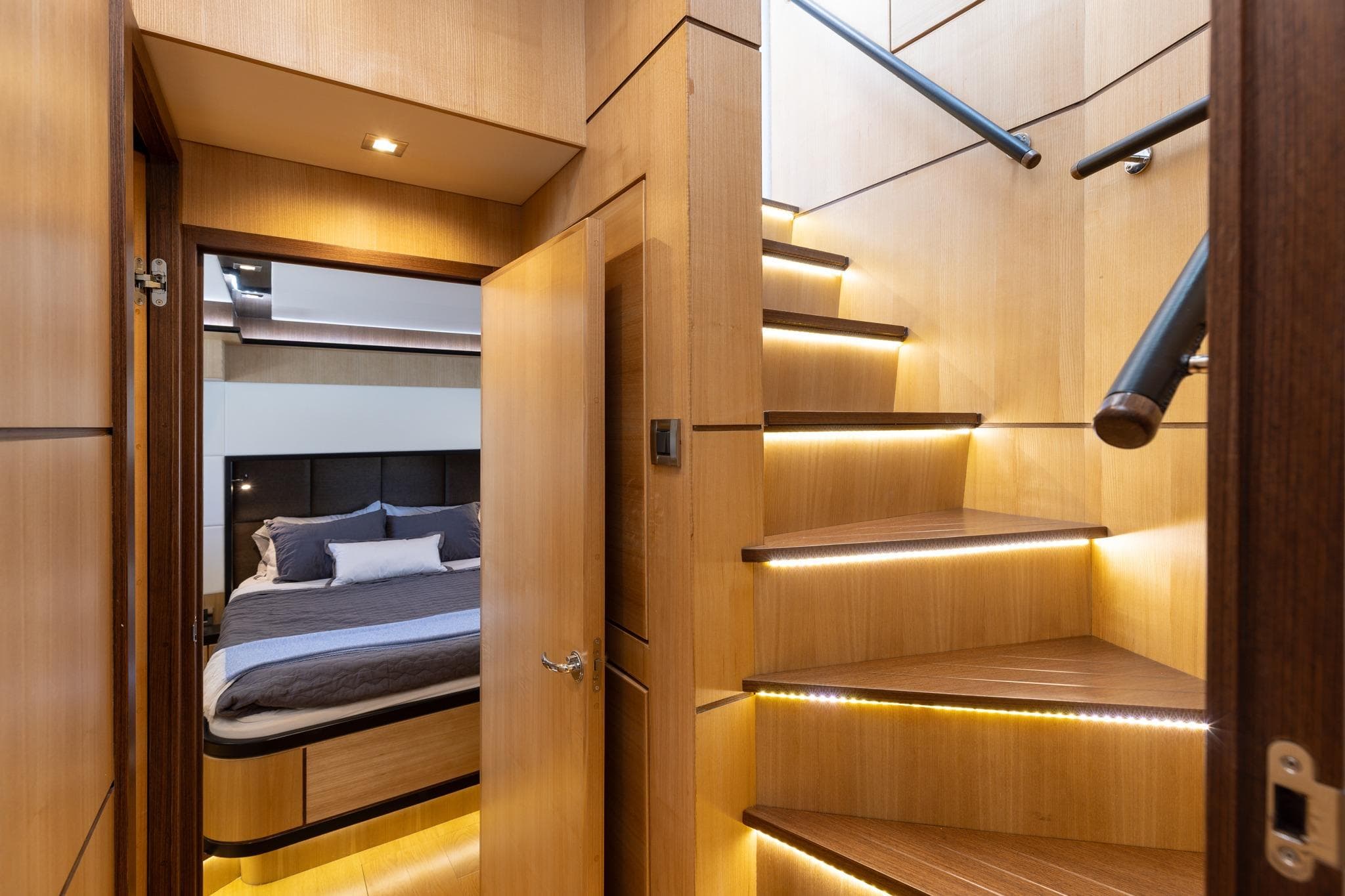 Luxurious interior of 2023 North Pacific 49 Euro yacht with modern staircase and cozy bedroom.