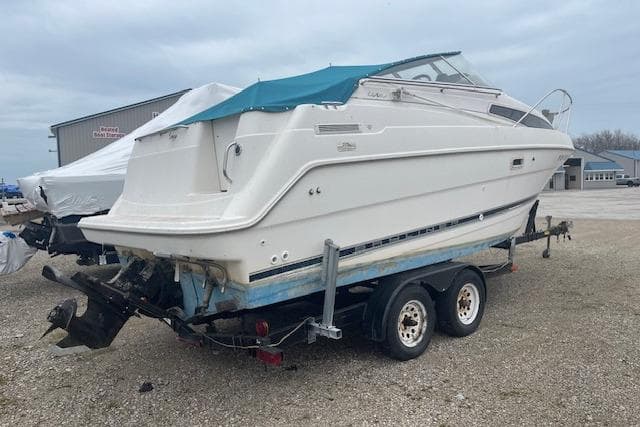 1997 Bayliner 2355 boat on trailer, parked outdoors, with a blue cover.