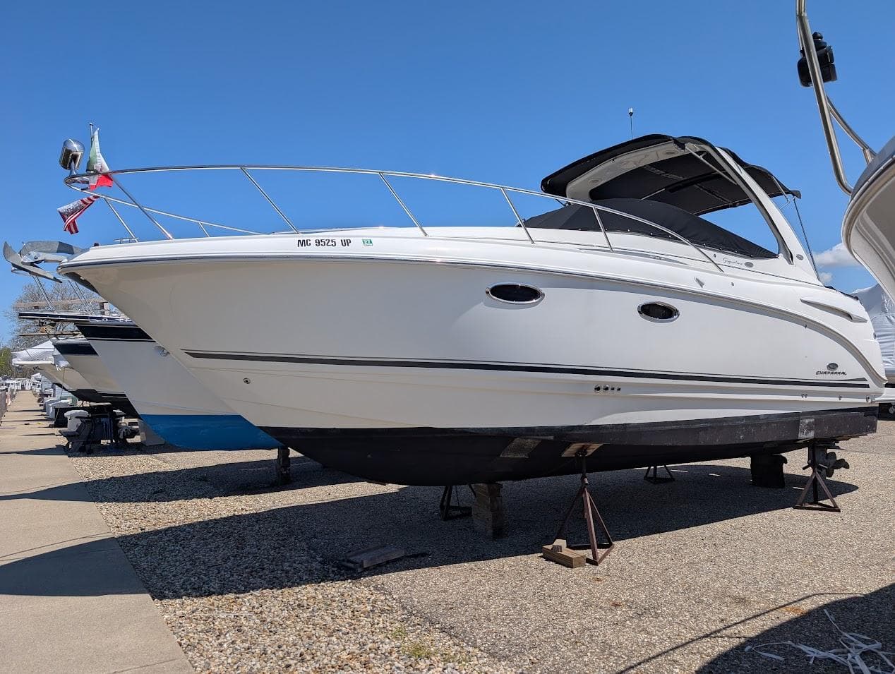 2006 Chaparral 310 Signature boat on stands, displayed outdoors under clear blue sky.