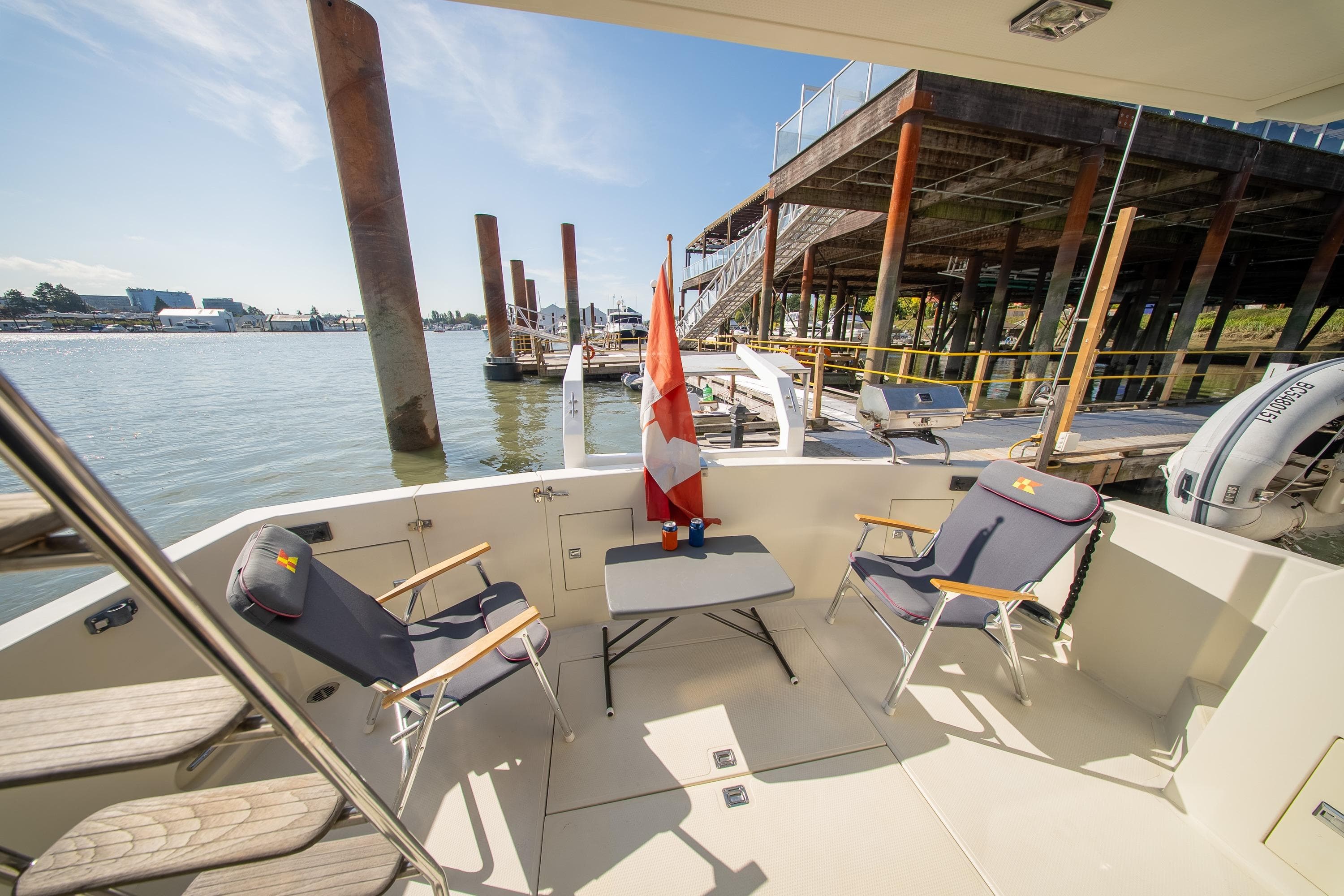 1990 Tollycraft 44 Sedan boat deck with chairs and table, docked by the water.