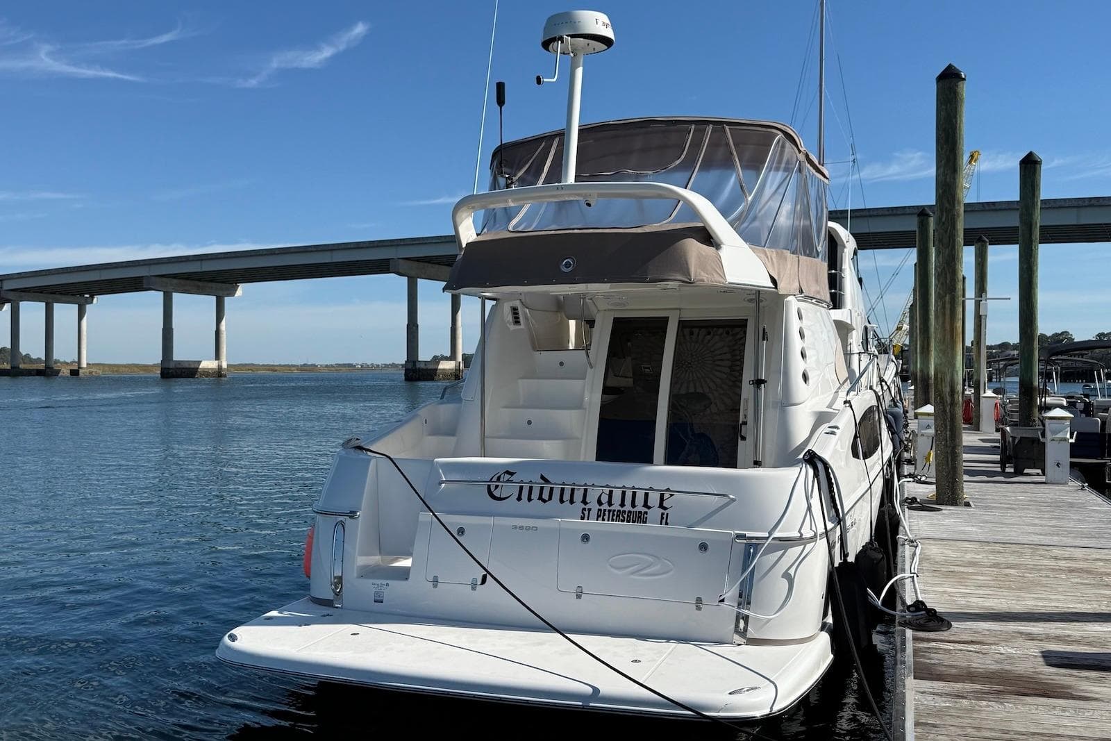 2003 Regal Commodore 3880 yacht docked by a bridge on a sunny day.