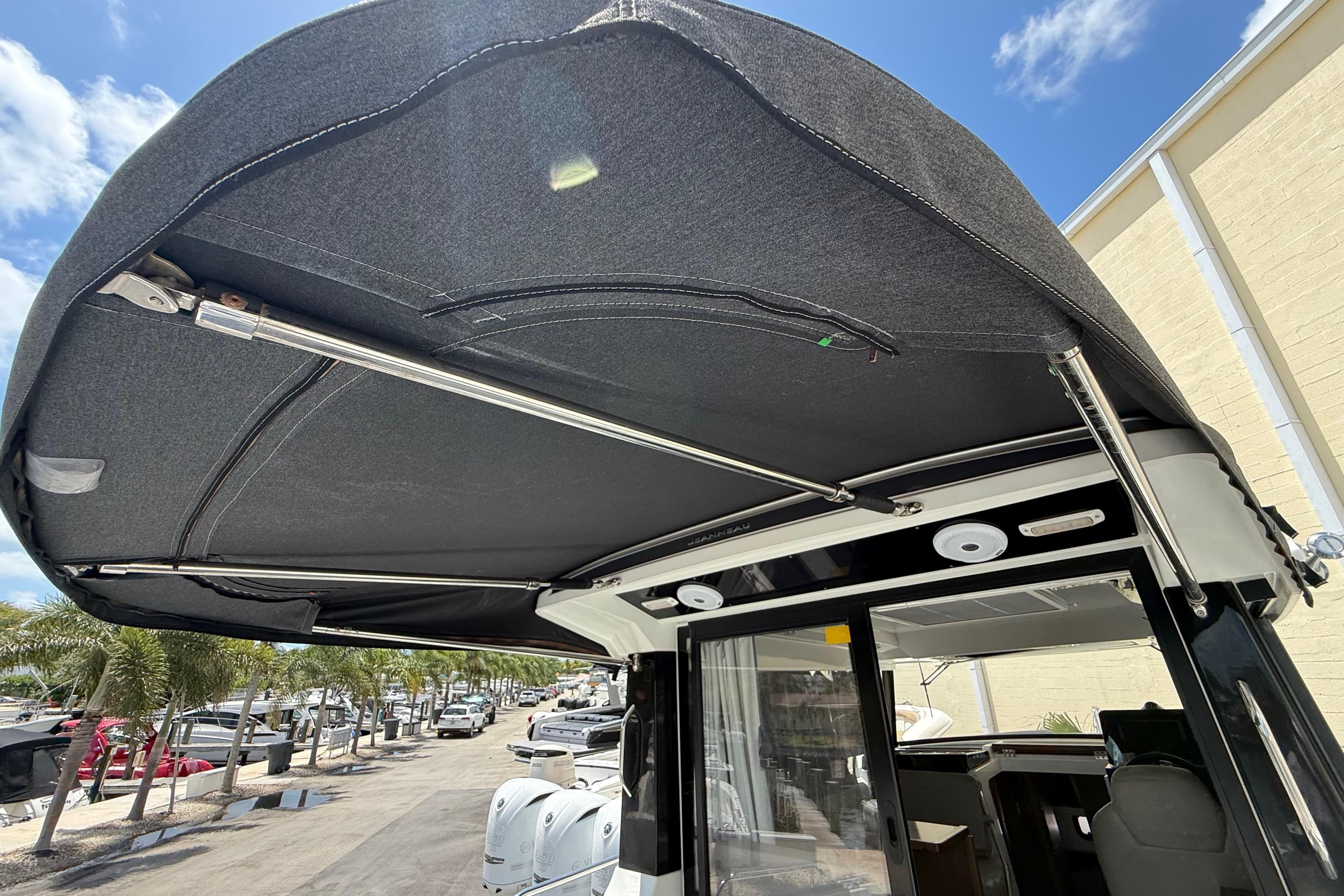 2021 Jeanneau NC 895 boat canopy with stainless steel supports, docked under a clear blue sky.