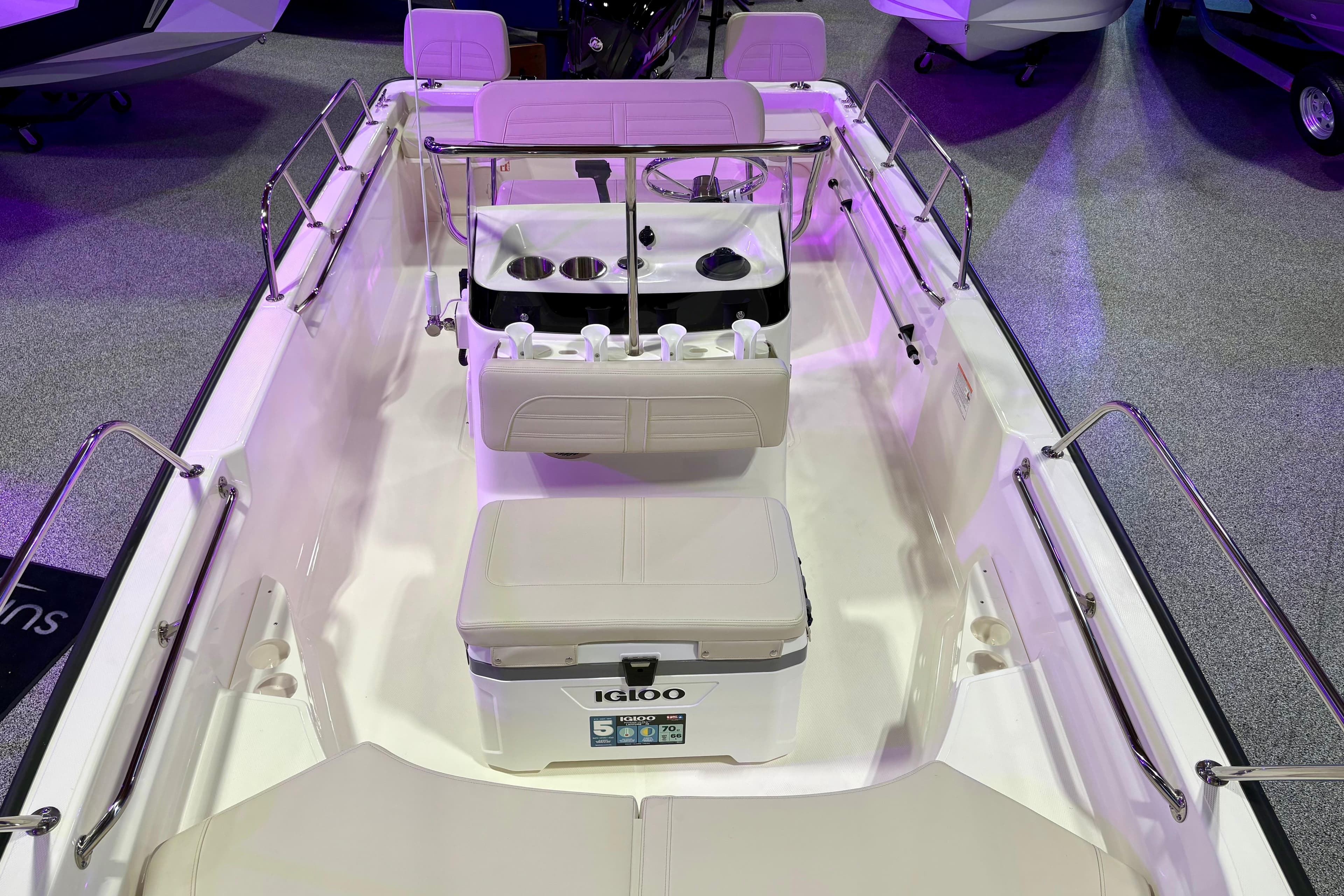 2026 Boston Whaler 170 Montauk interior with seating and cooler, showcased under purple lighting.