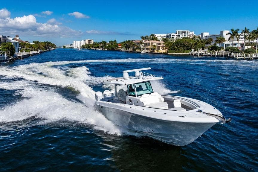 2024 HCB 42 Lujo boat cruising on a sunny waterway with luxury homes.