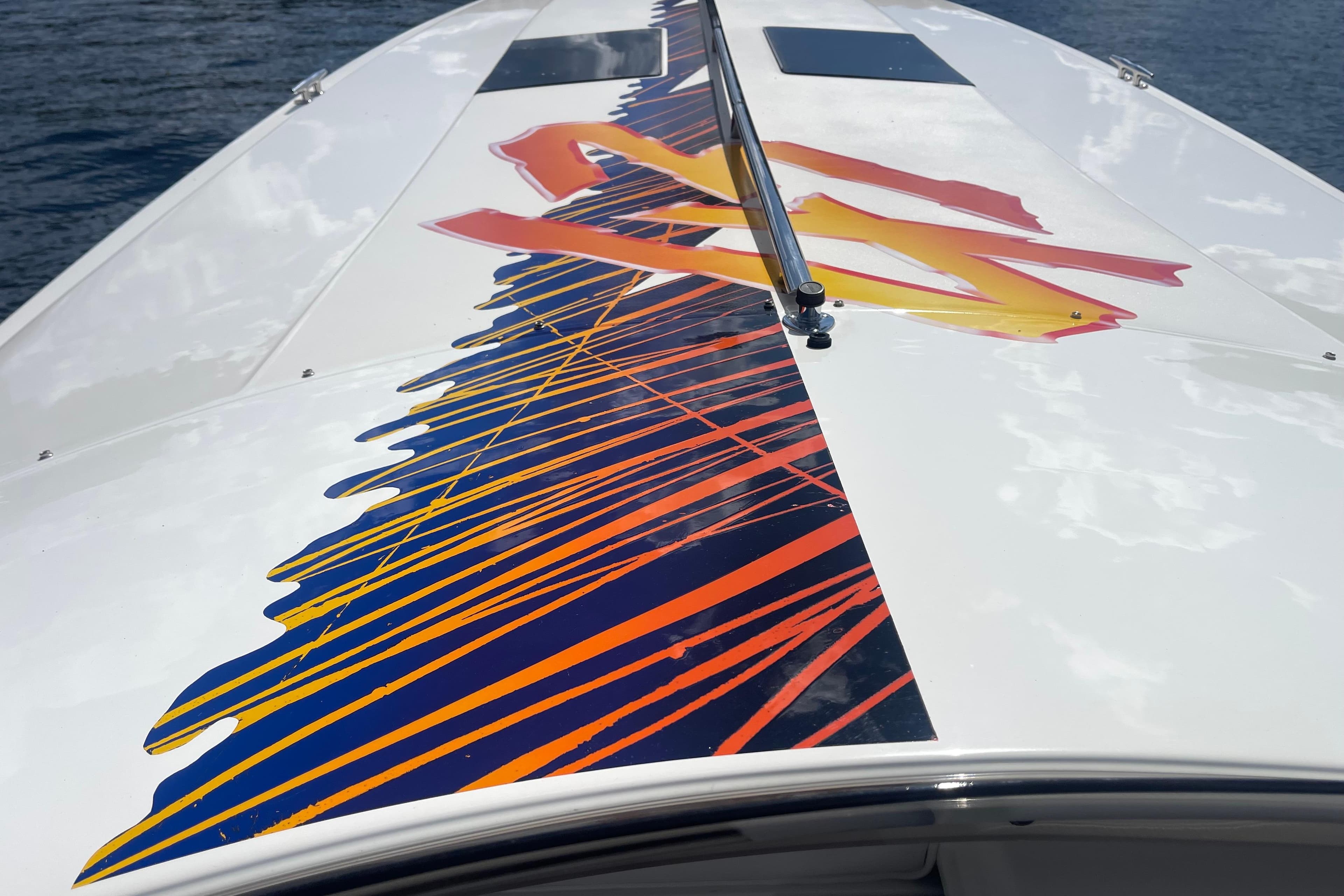 1995 Excel Scarab 43 boat with vibrant orange and blue graphics on deck.