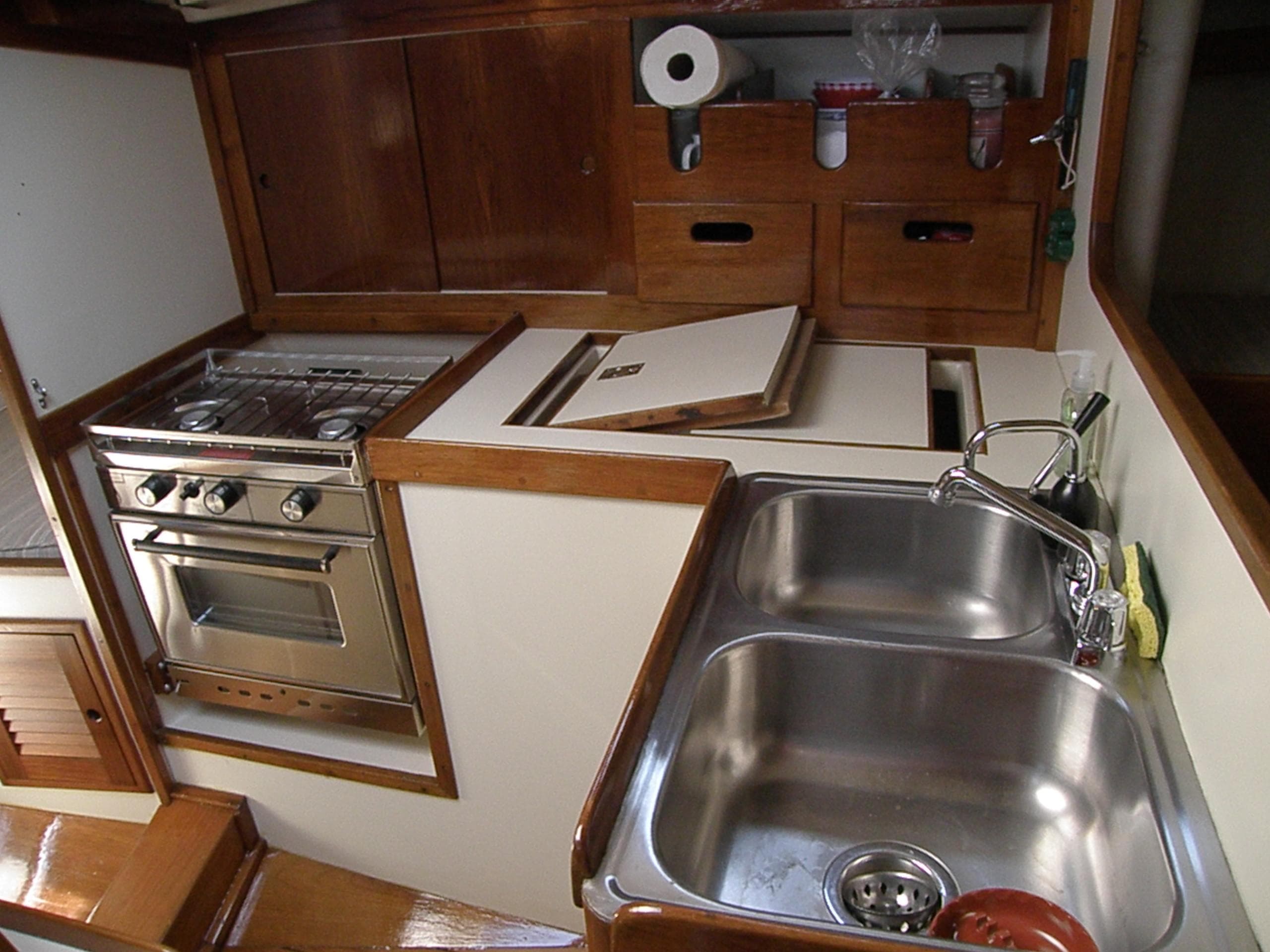 1972 Tartan 41 yacht kitchen with stainless steel sink, stove, and wooden cabinetry.