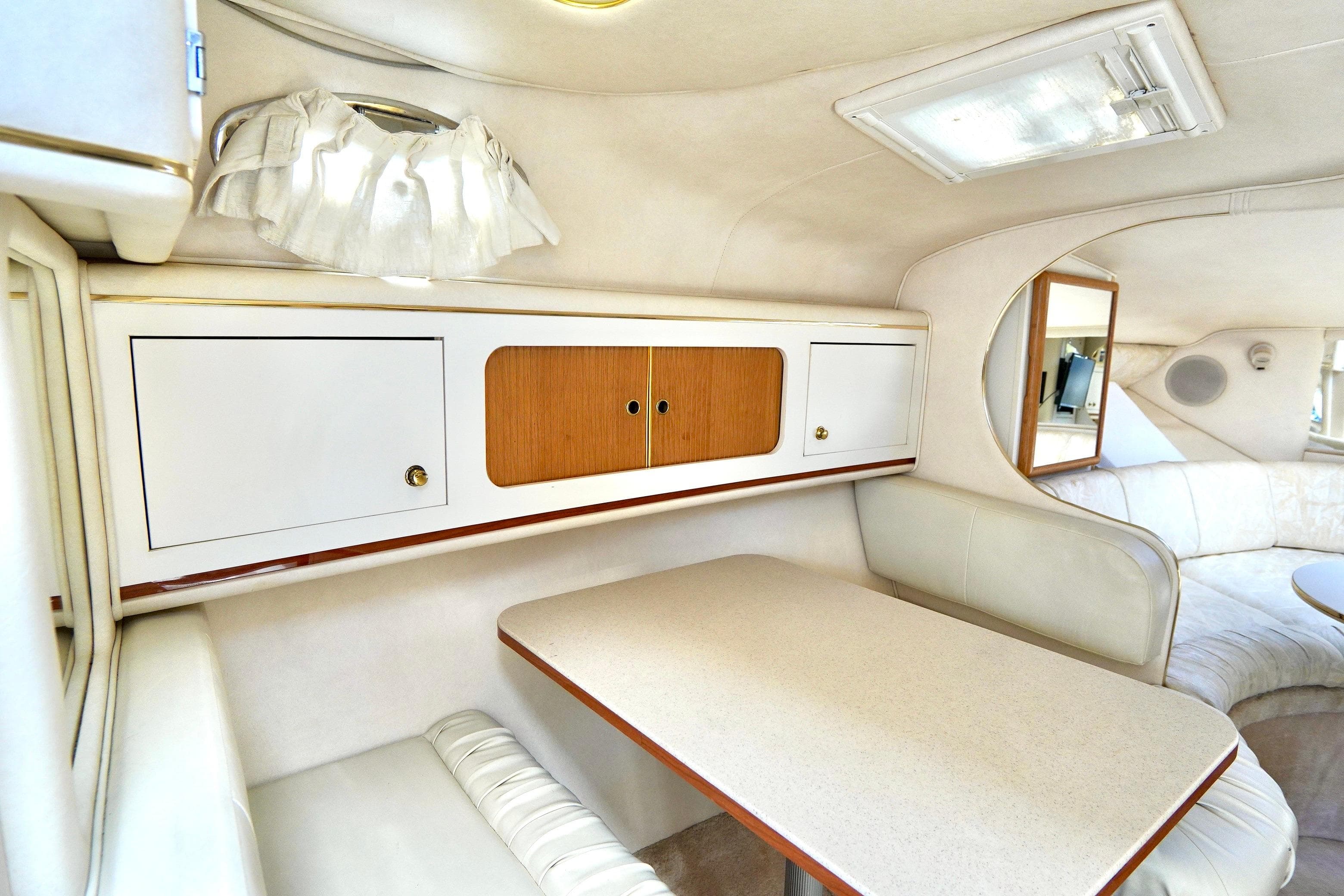 Interior of 2000 Sea Ray 280 Sundancer, featuring a cozy dining area with white cabinetry.