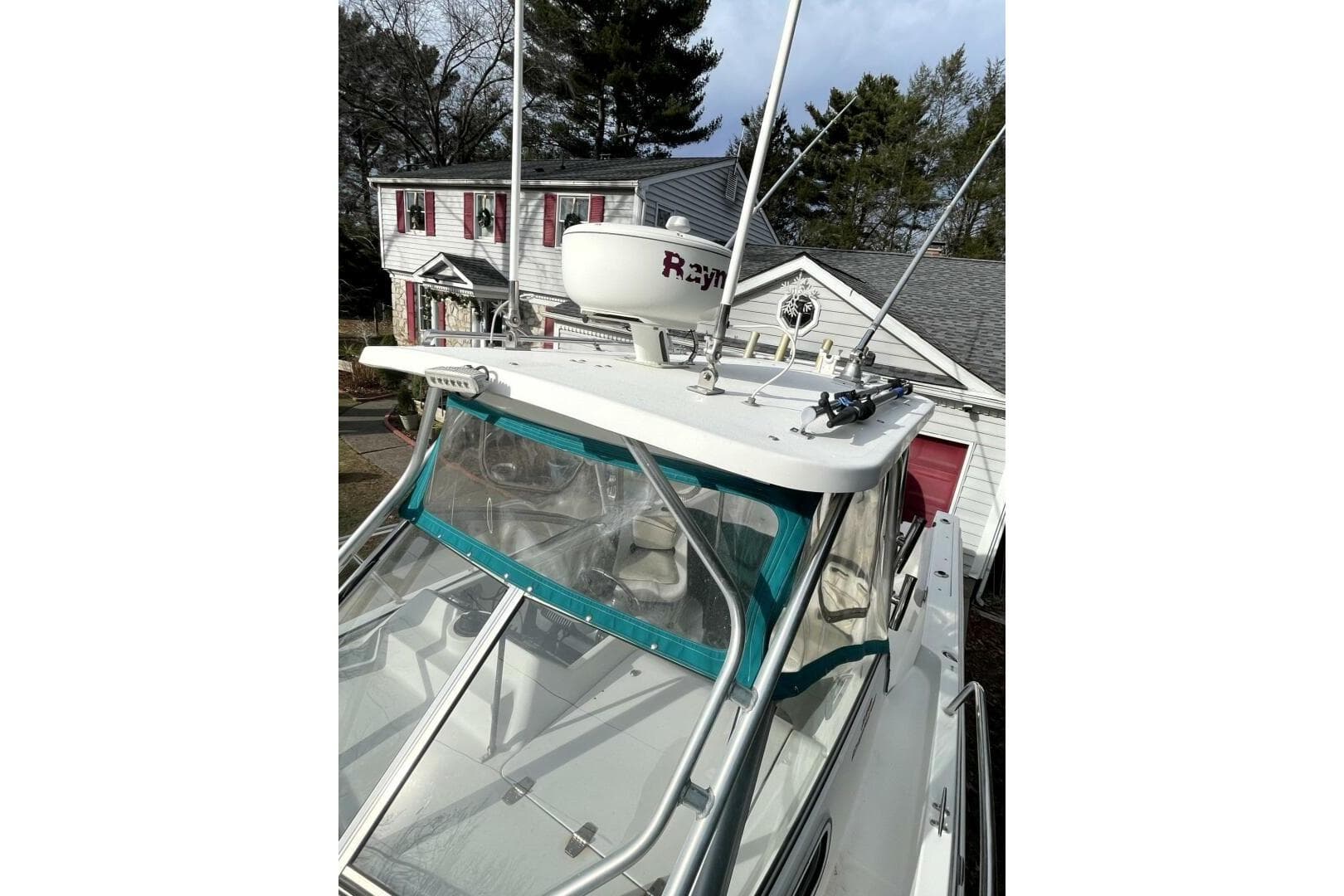 2001 Aquasport 250 Explorer boat with radar, parked near a house.