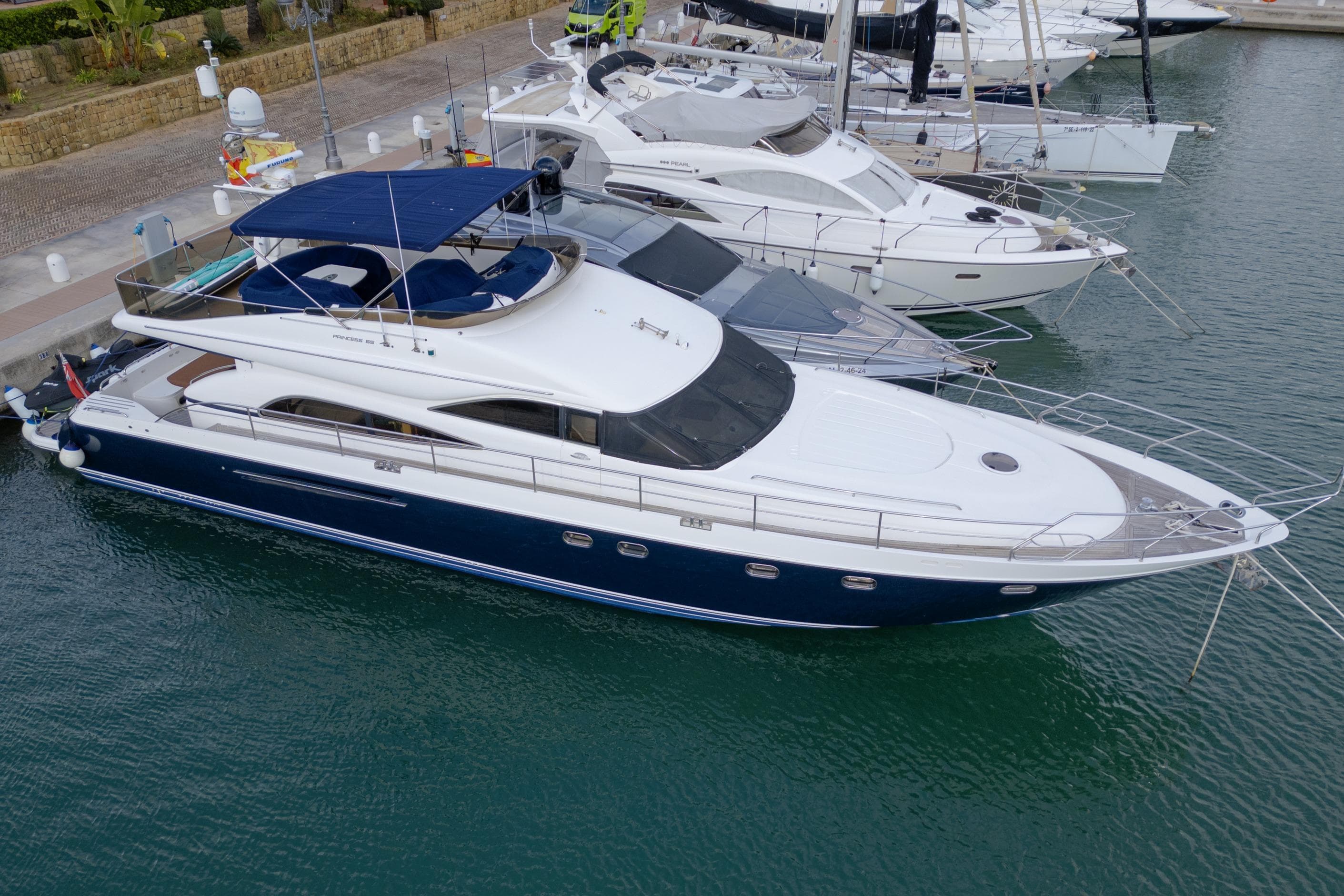 Luxury 2003 Princess 65 yacht docked in marina, featuring sleek design and blue hull.