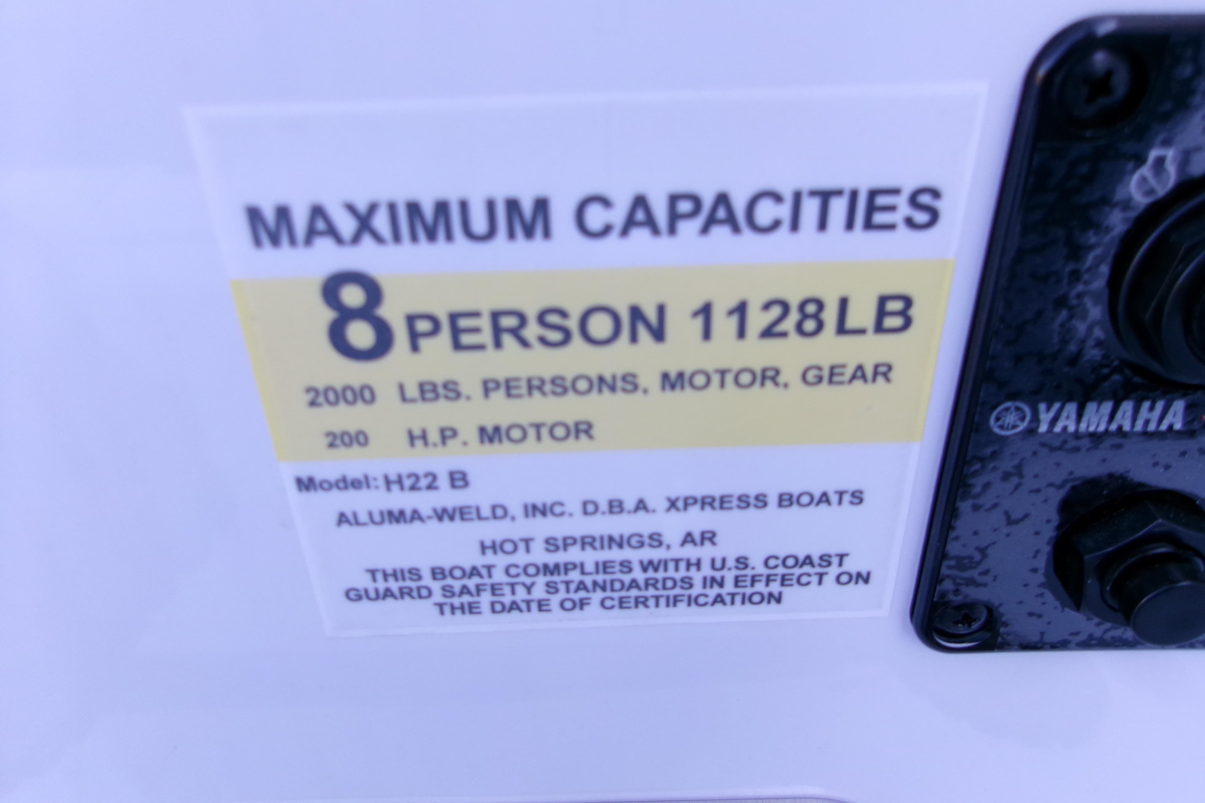Maximum capacity label on 2026 Xpress H22B Bay boat, 8 persons, 2000 lbs, 200 HP motor.
