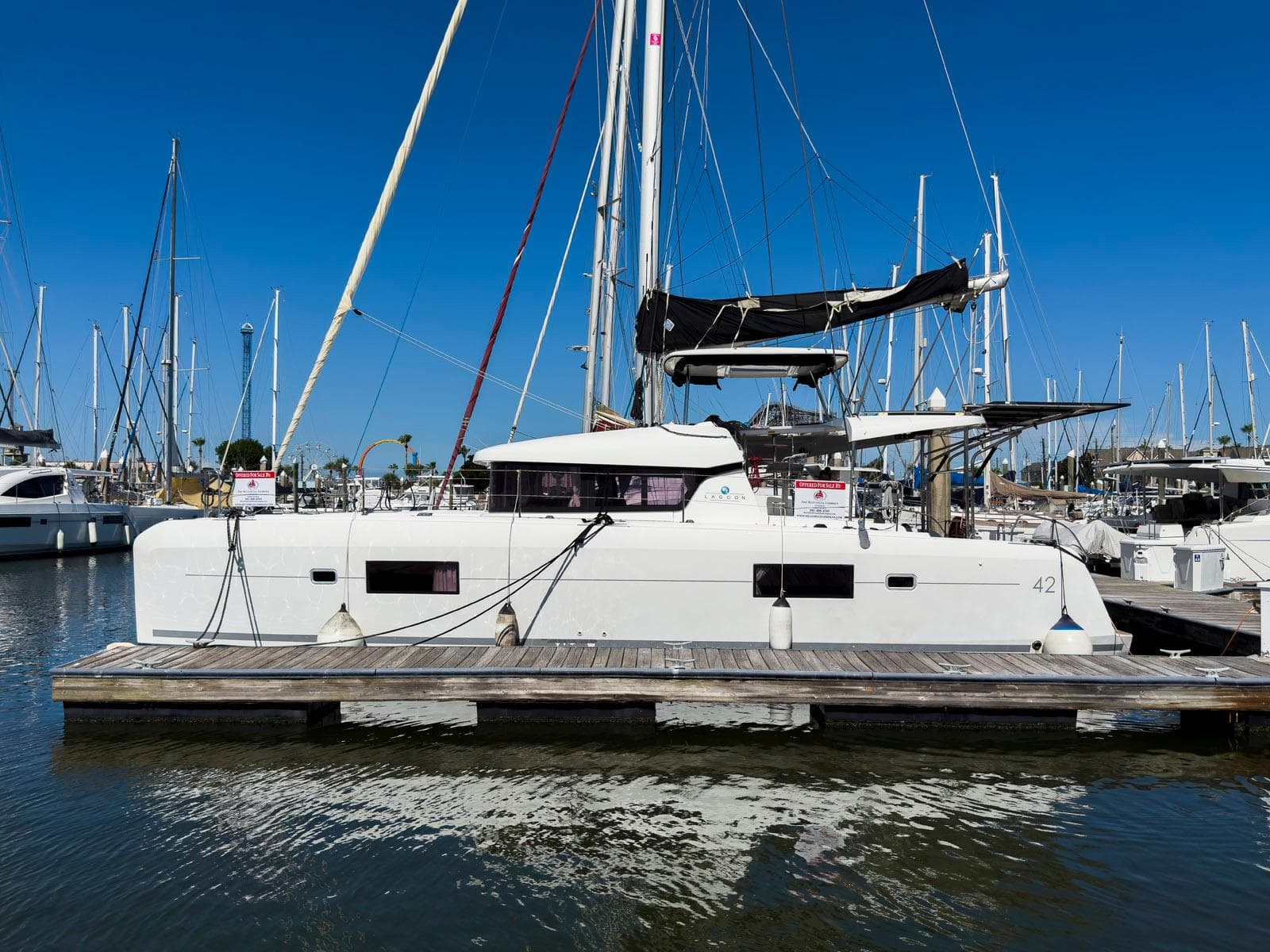 2017 Lagoon 42 catamaran docked at marina under clear blue sky.
