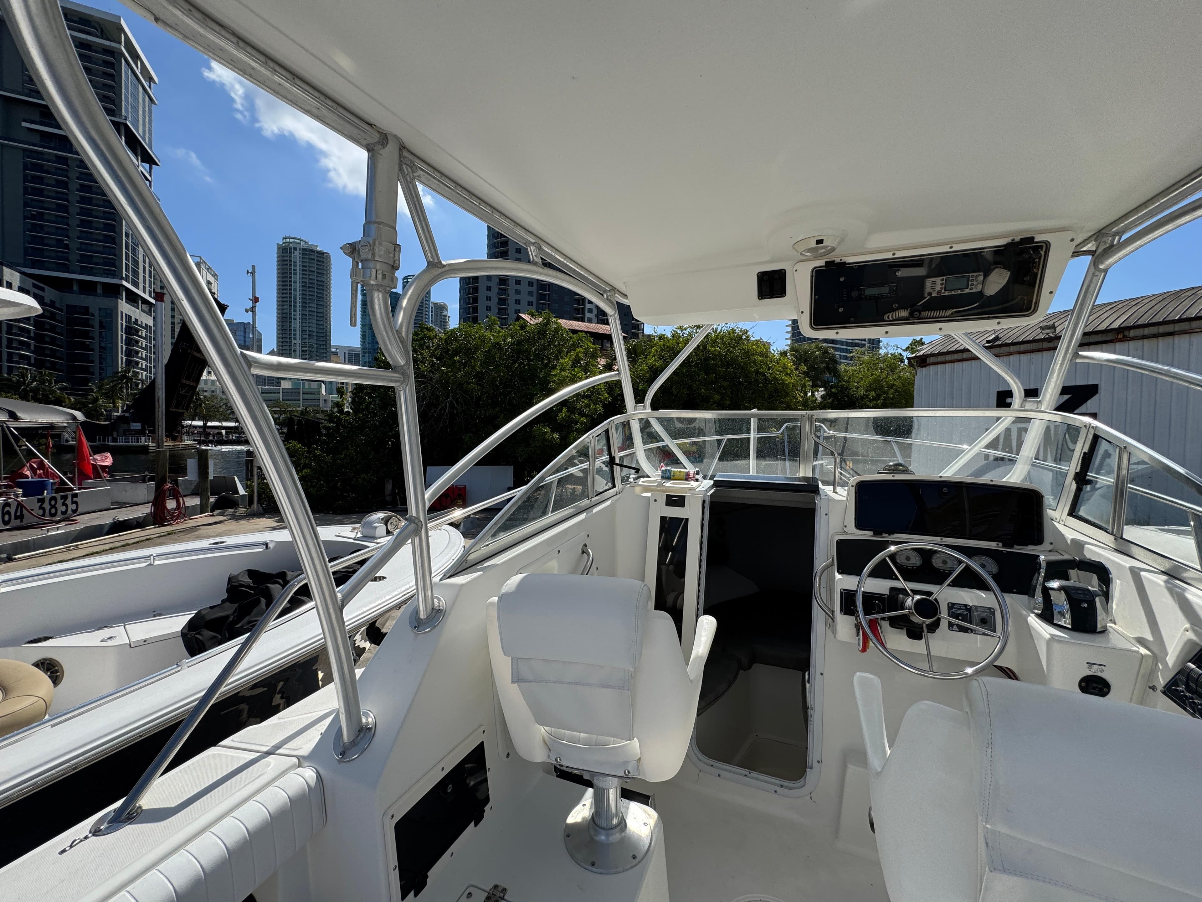 1999 Boston Whaler Conquest 23 boat interior with steering wheel and city skyline background.