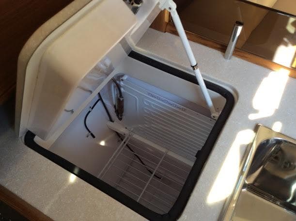 Open storage compartment in Catalina 426 yacht, 2026 model, with white interior and metal hinge.