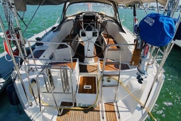 2009 Delphia 40.3 sailboat with spacious cockpit and wooden deck, docked on calm water.