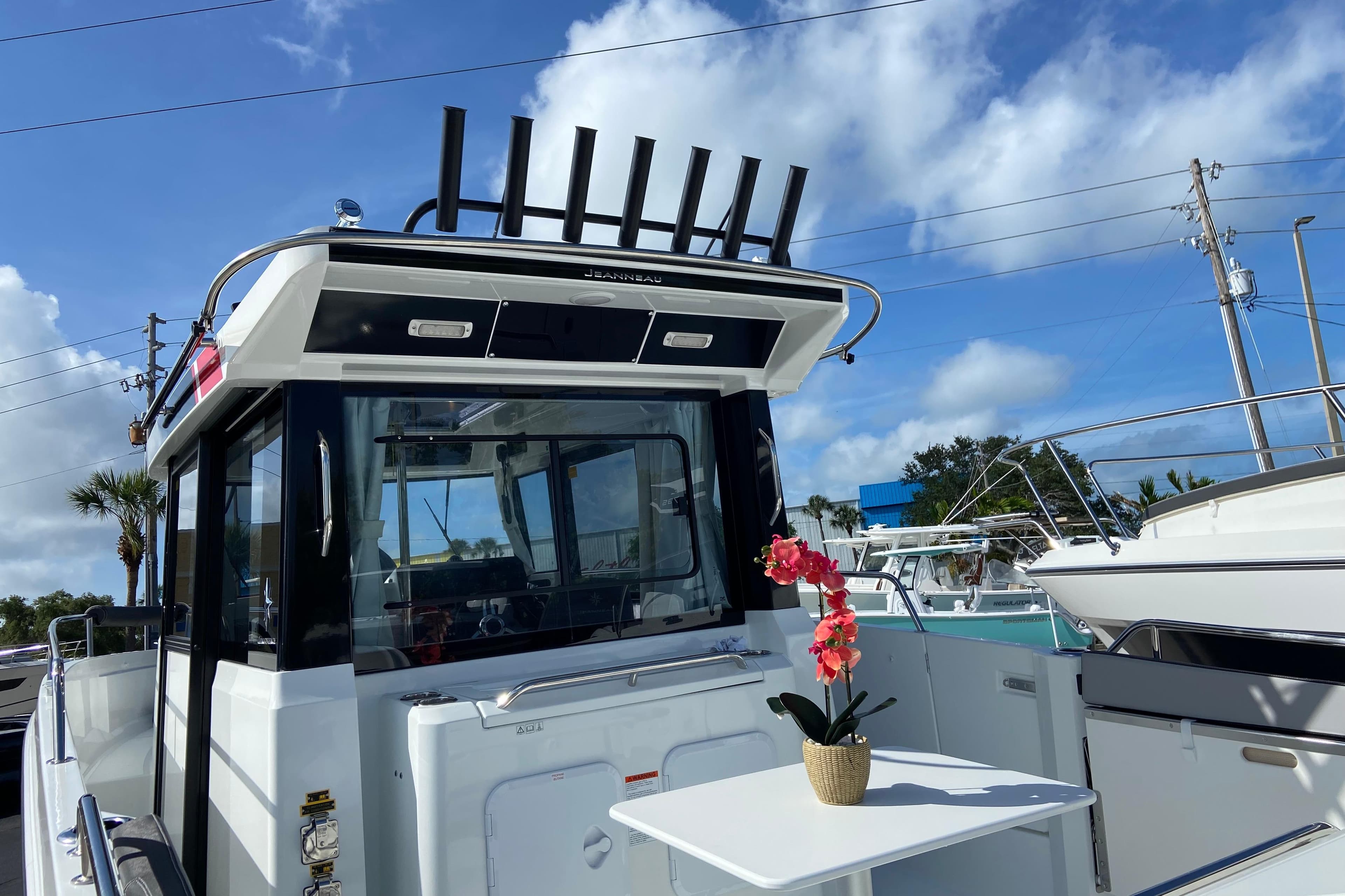 2026 Jeanneau NC Sport 795 Series 2 boat with table and flower, under blue sky.