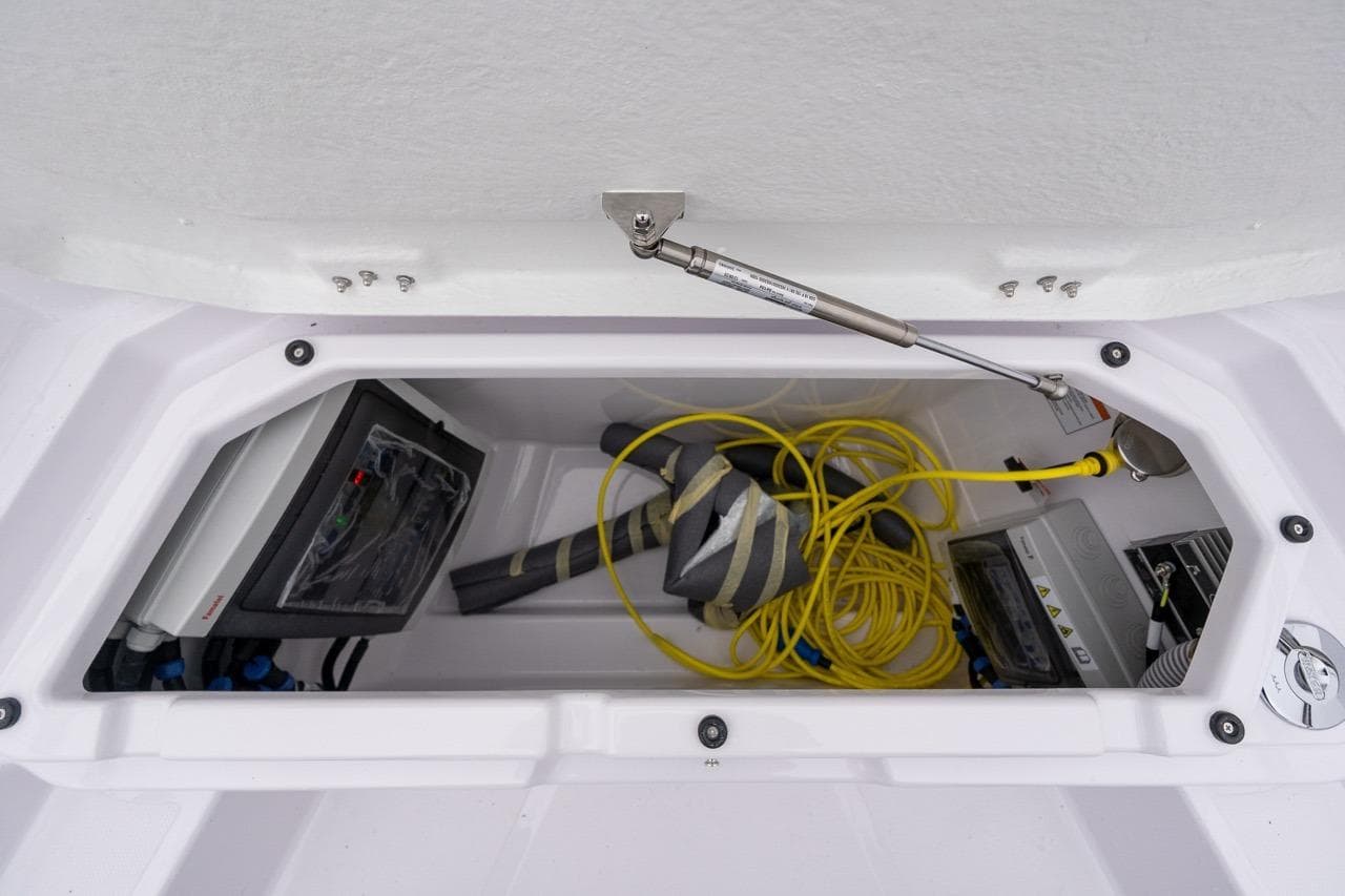 Storage compartment of 2027 Axopar 38 Cross Cabin with equipment and yellow cable.