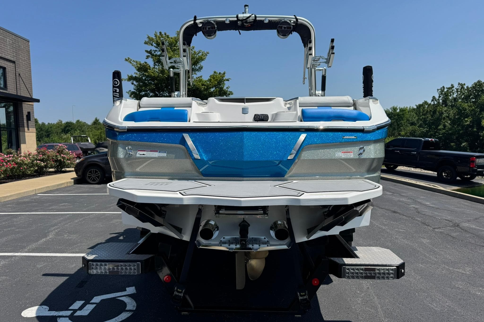2020 MasterCraft X24 boat in parking lot, rear view, blue and white design.