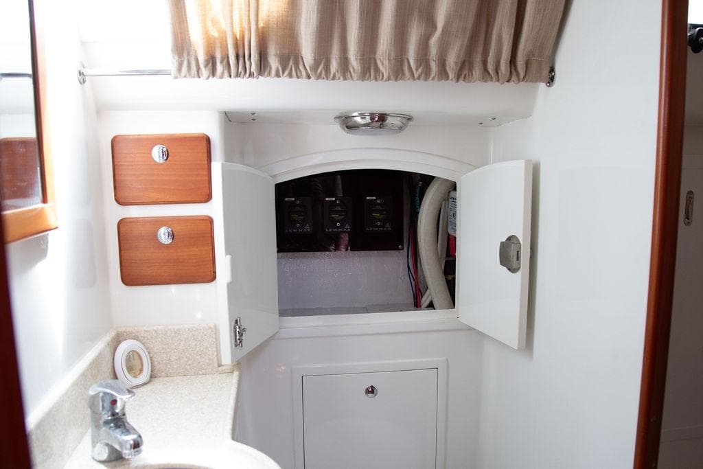 Interior of 2015 Outbound 46 yacht showing storage cabinets and plumbing access.