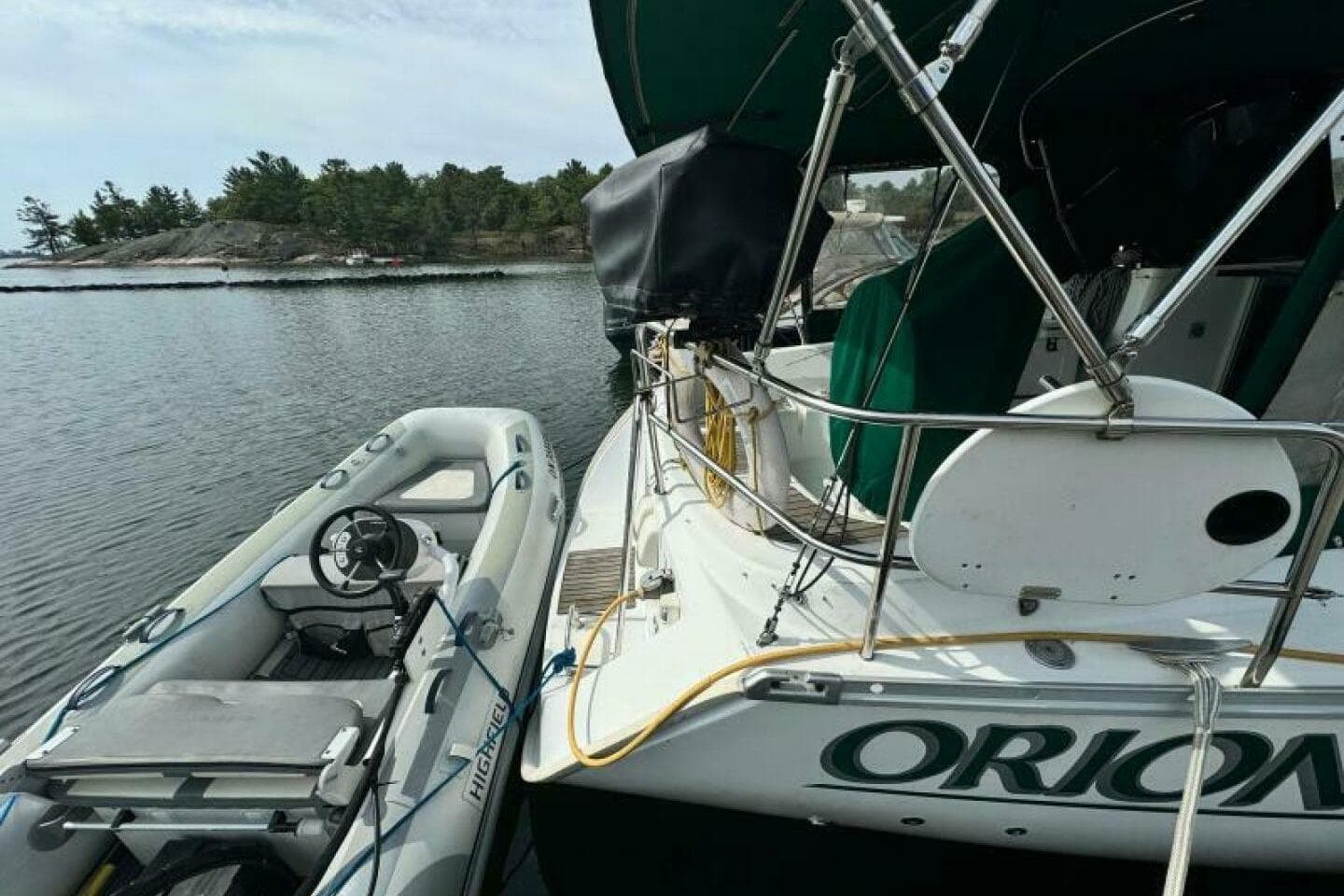 Beneteau 323 sailboat from 2004 docked with inflatable dinghy on calm water.