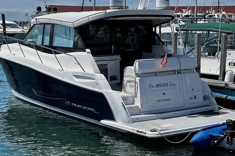 2024 Regal 38 Grande Coupe yacht docked in marina, rear view with American flag.