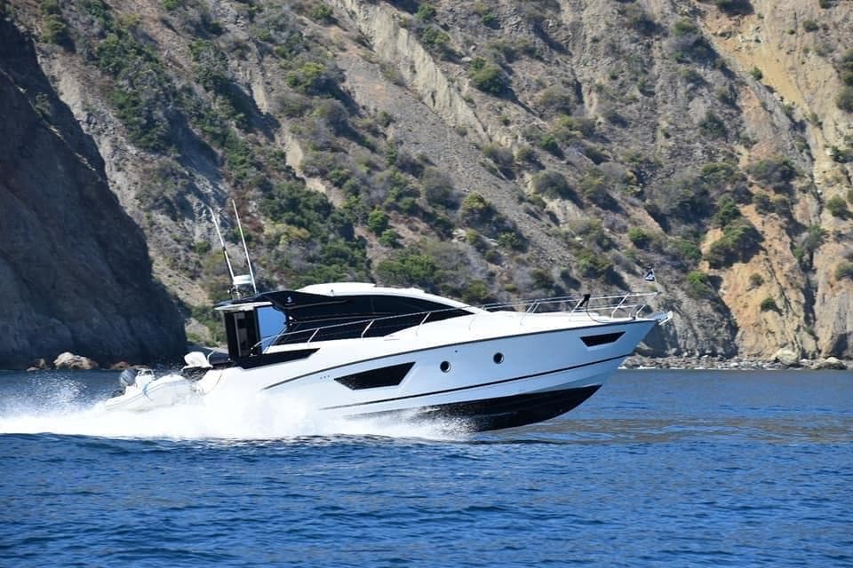 2017 Beneteau Gran Turismo 46 yacht cruising near rocky coastline.