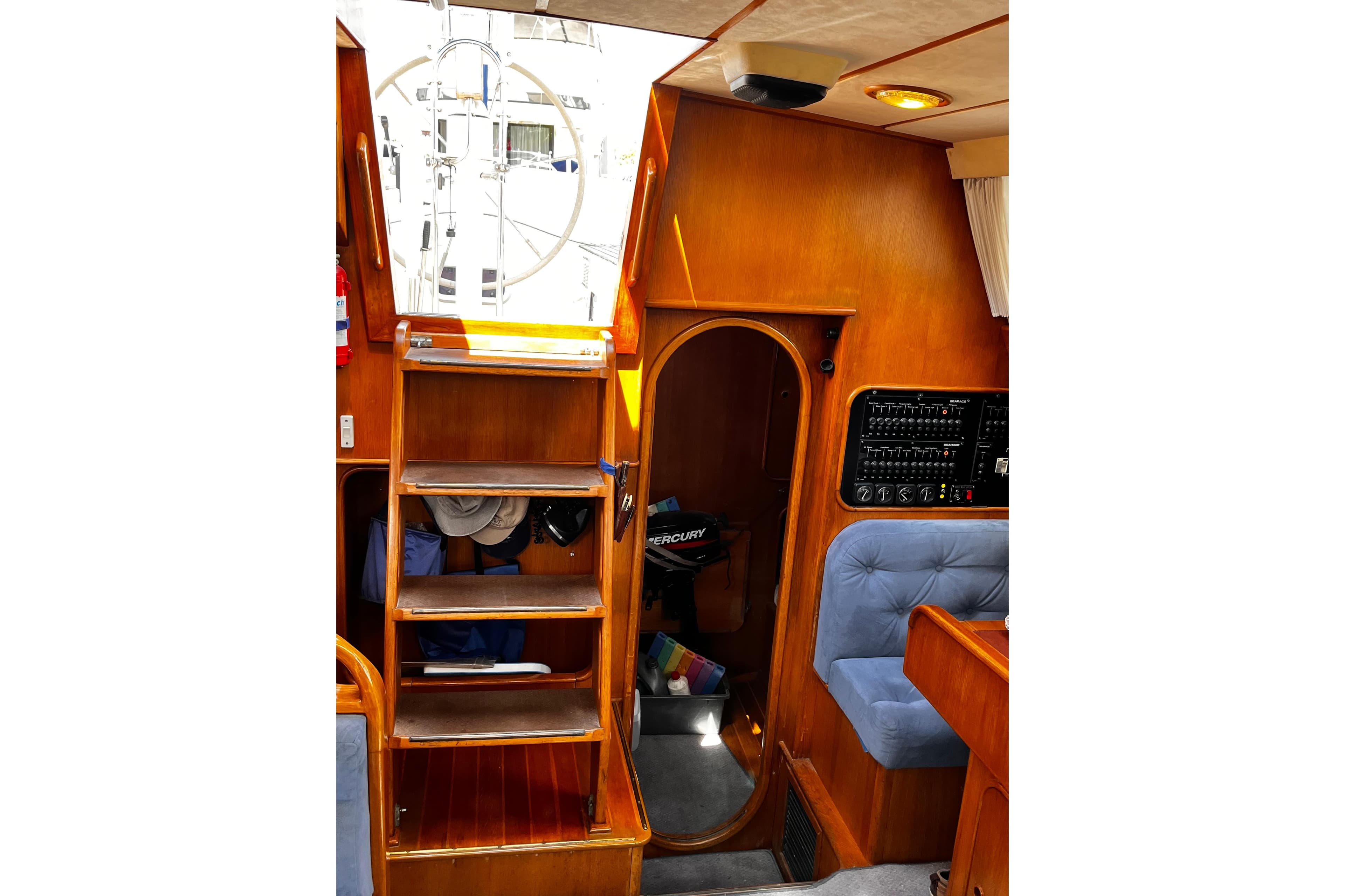Interior of 1989 Oyster 53 Deck Saloon with wooden stairs and control panel.