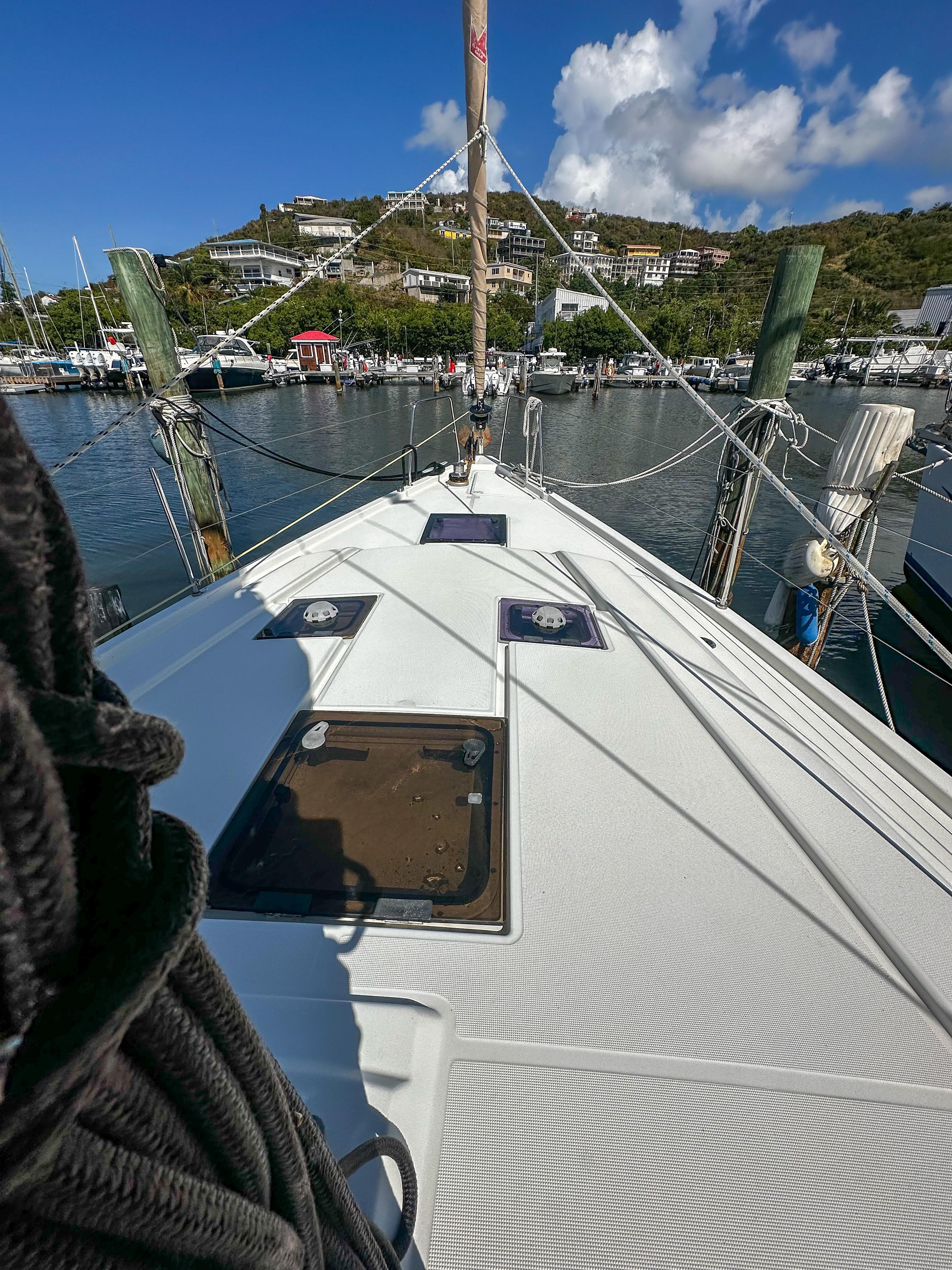 2018 Beneteau Oceanis 41.1 sailboat docked in a marina, clear sky, and hillside view.
